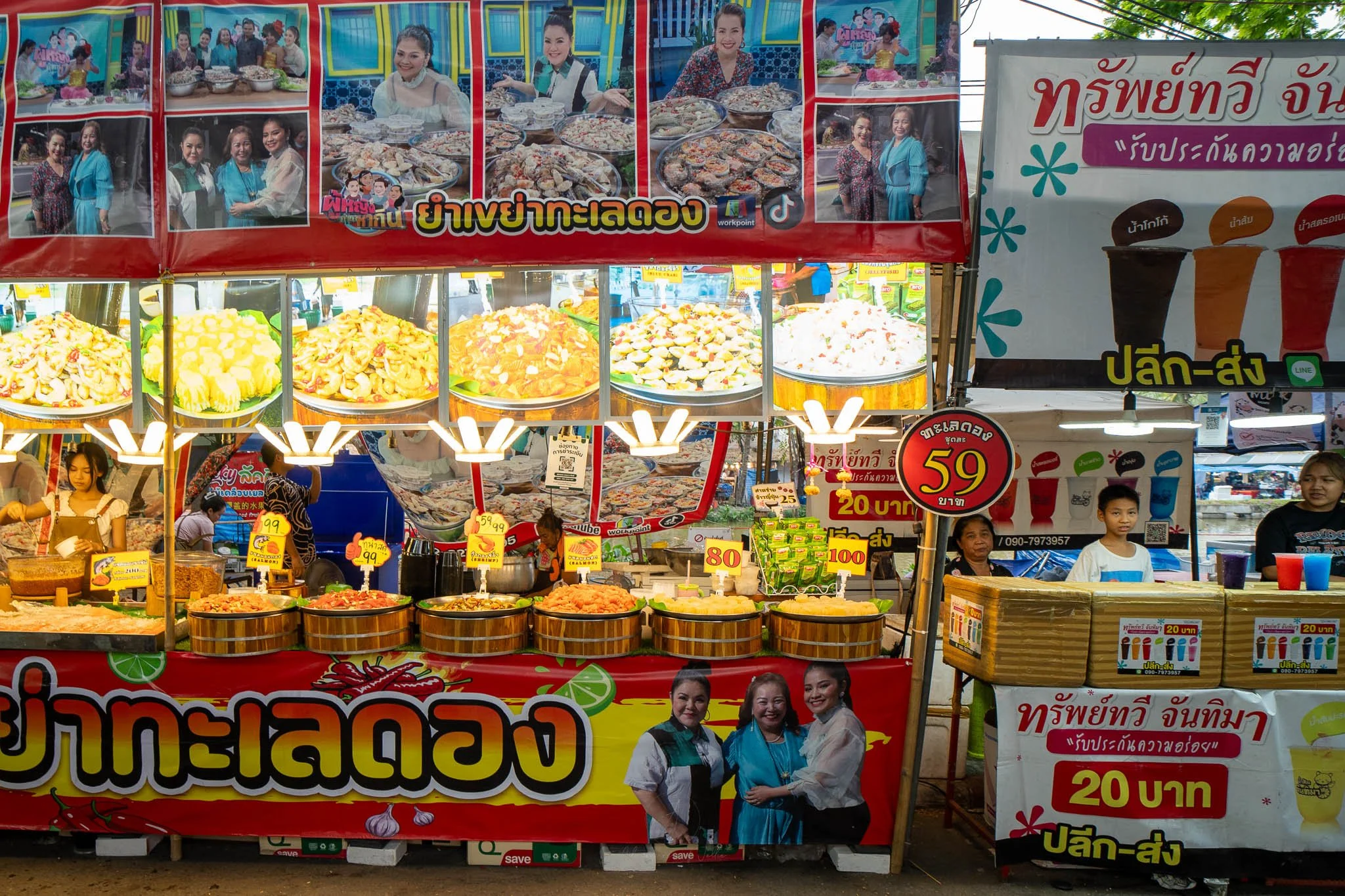 Two street food stalls line the road at the Kaset Fair. On the left, the stall is selling baskets of dried shrimp and other shellfish, whilst the stall to the right sells colourful iced drinks.