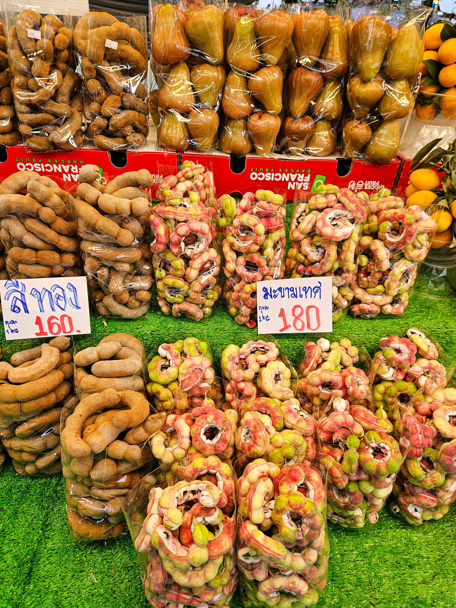 Clear bags are stuffed full of Tamarind ready to be sold at a fruit and vegetable stall at the Kaset Fair Market in Bangkok.