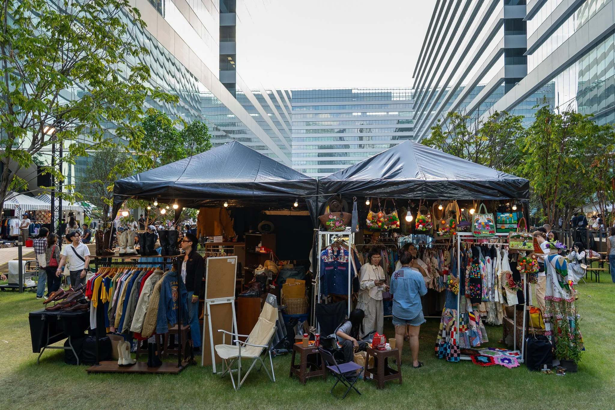 Sitting underneath two navy blue gazebos are two vintage cloth stalls selling colourful dresses and jackets at the Made By Legacy Flea Market in Bangkok.