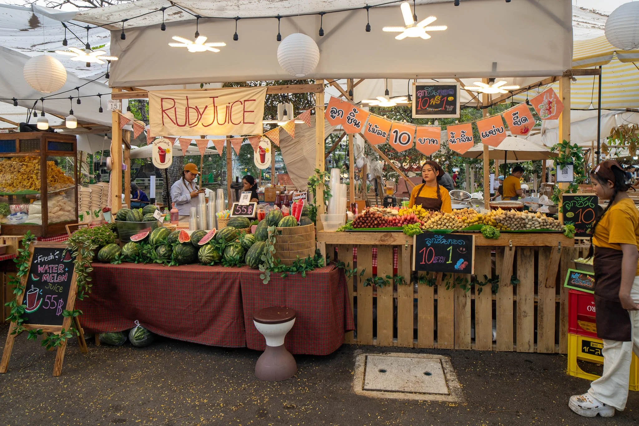 A watermelon juice stall sits next to a meat on sticks street food stall at the Kaset Fair Market in Bangkok.