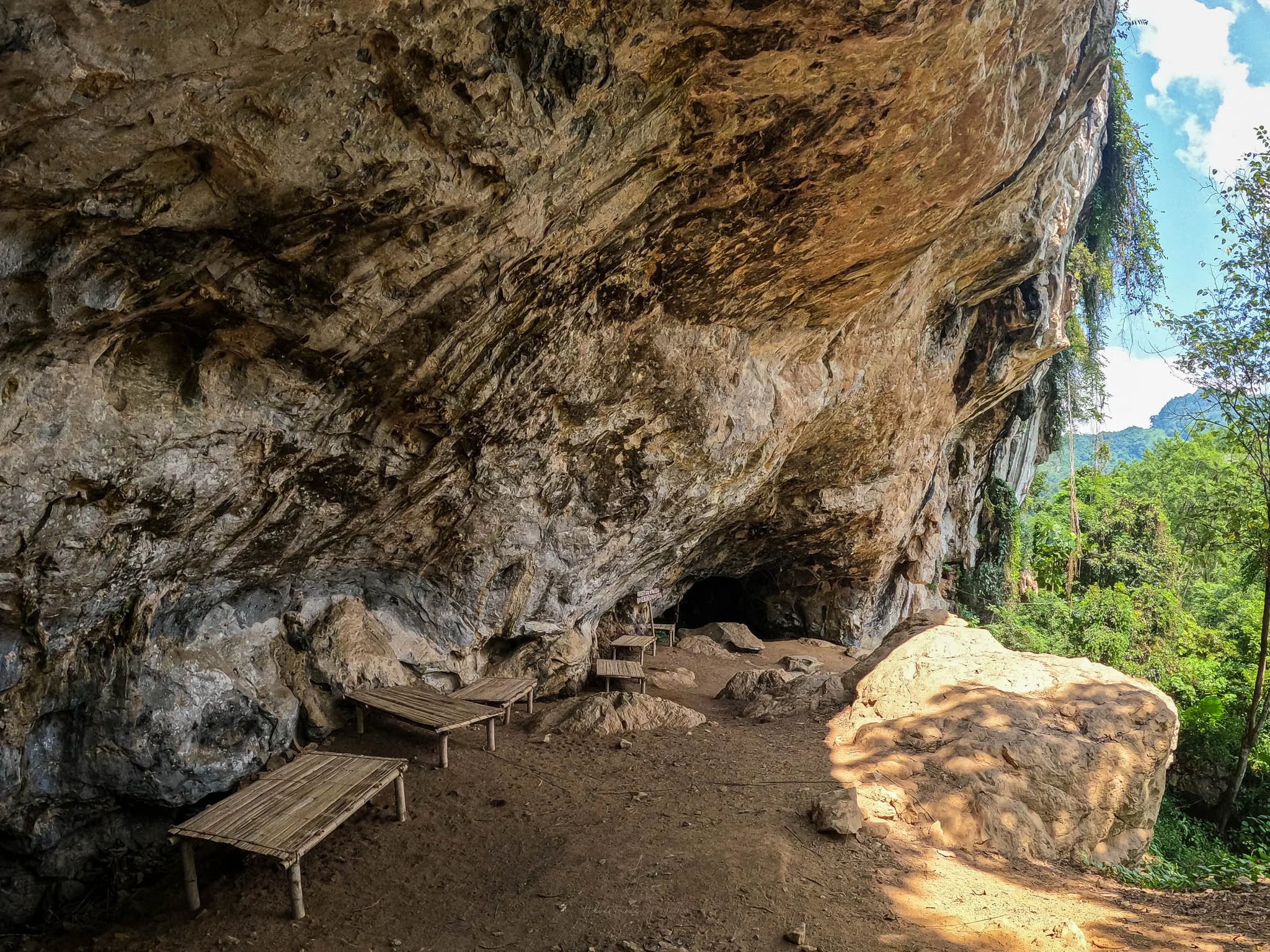 Old wooden bamboo beds sit scattered around the entrance to a cave which was once used for shelter during the Secret War. Photo taken at the Ban Pha Toke museum in Nong Khiaw, Laos.
