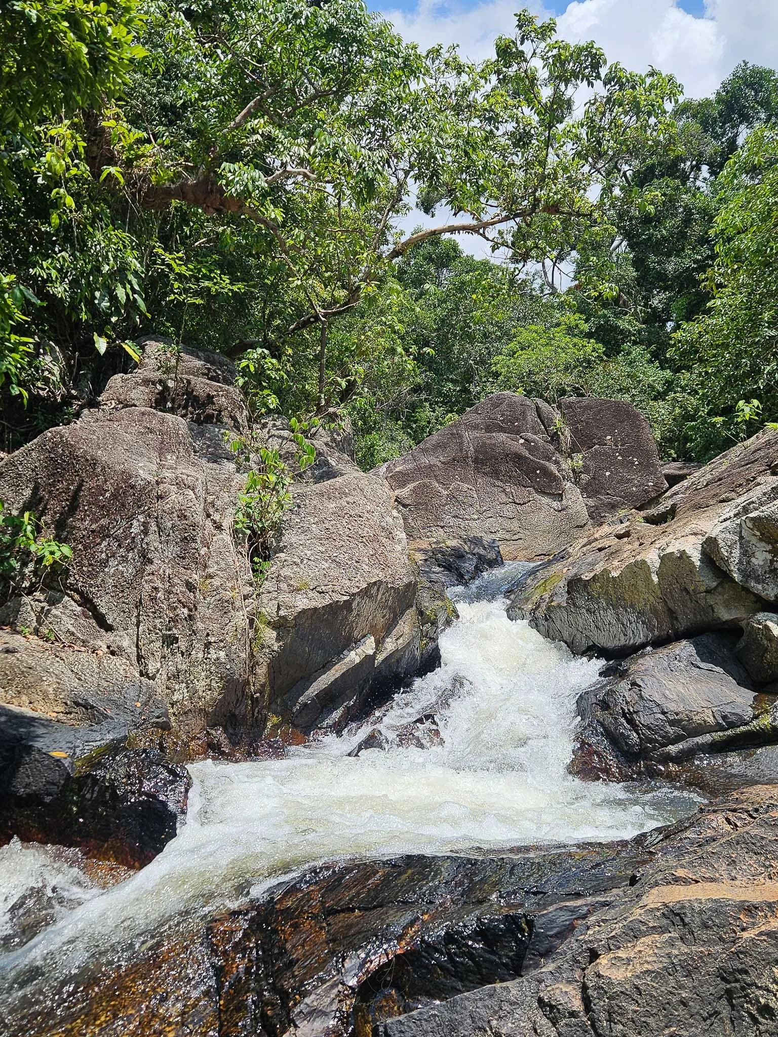 White water cascades down jagged grey rocks in the middle of a jungle in Namtok Than Sadet National Park on Koh Phangan.