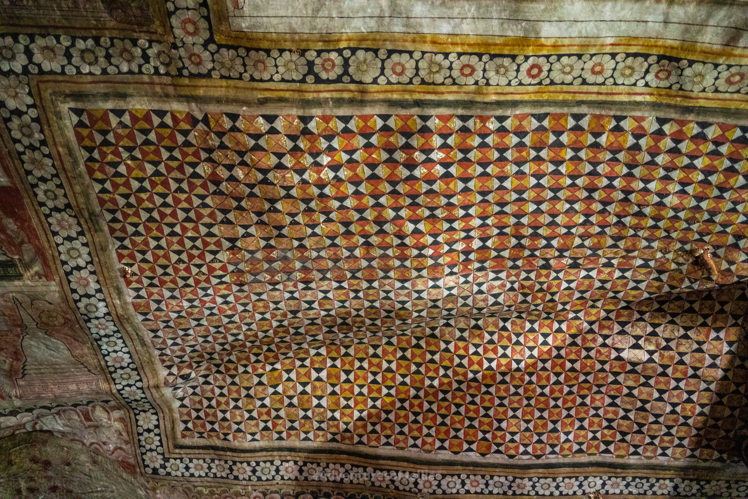 A whirl of chequered patterns and colours over the natural rock ceiling of the Dambulla Royal Cave Temple.