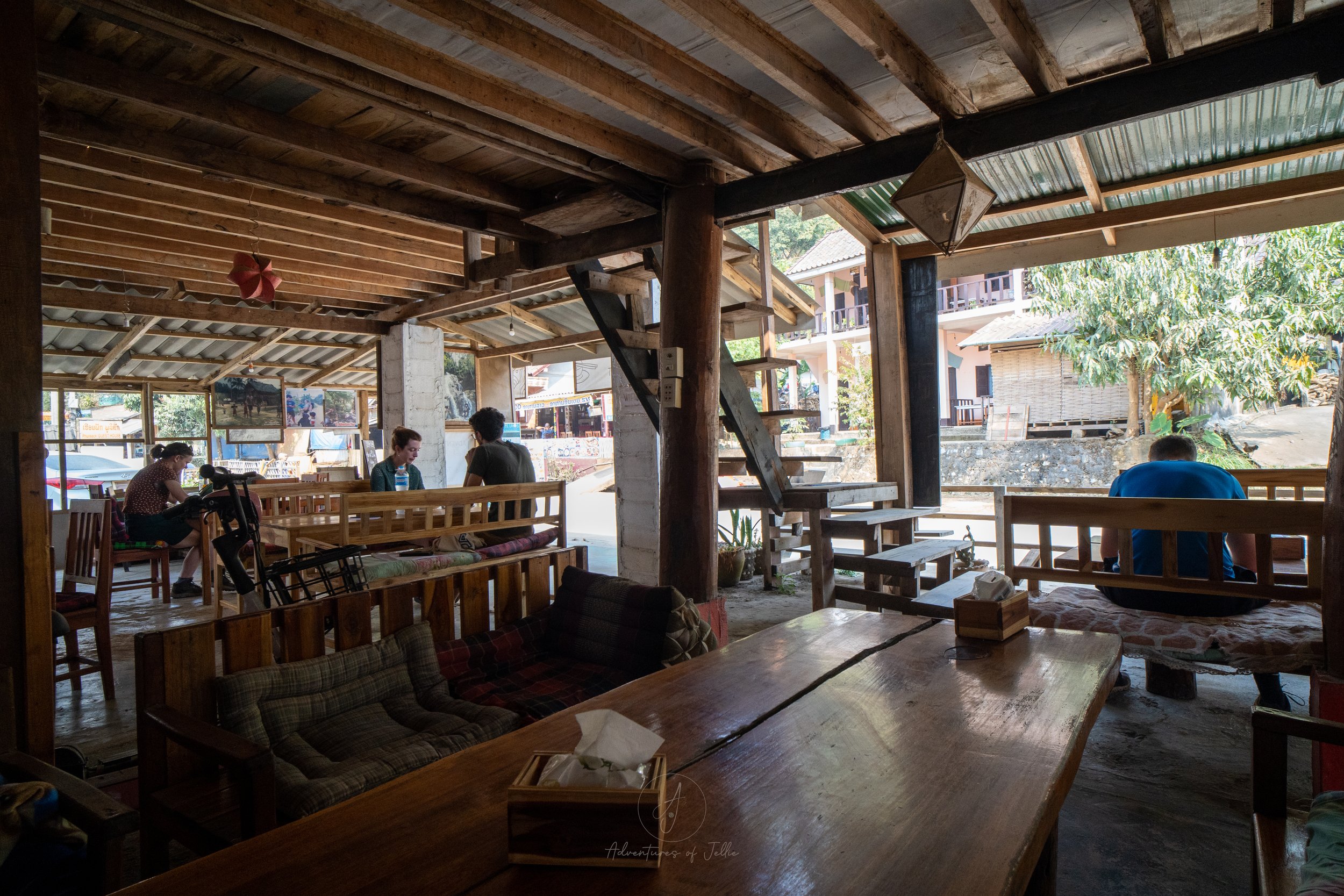The wooden interior of the Q Bar and Restaurant of Nong Khiaw is filed with travellers sitting and chatting at long wooden benches and tables.