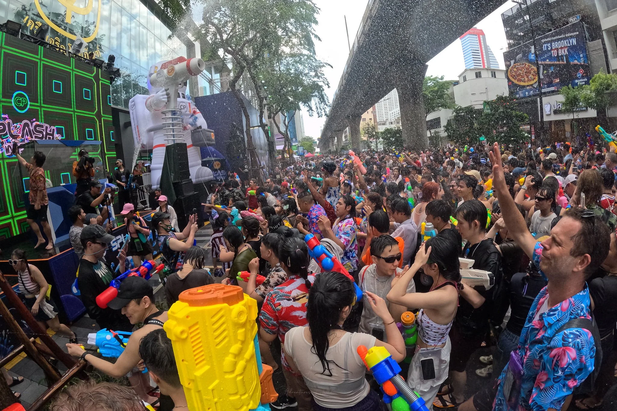 A crowd parties in front of a DJ booth on Silom road, spray from waterpistols is everywhere.