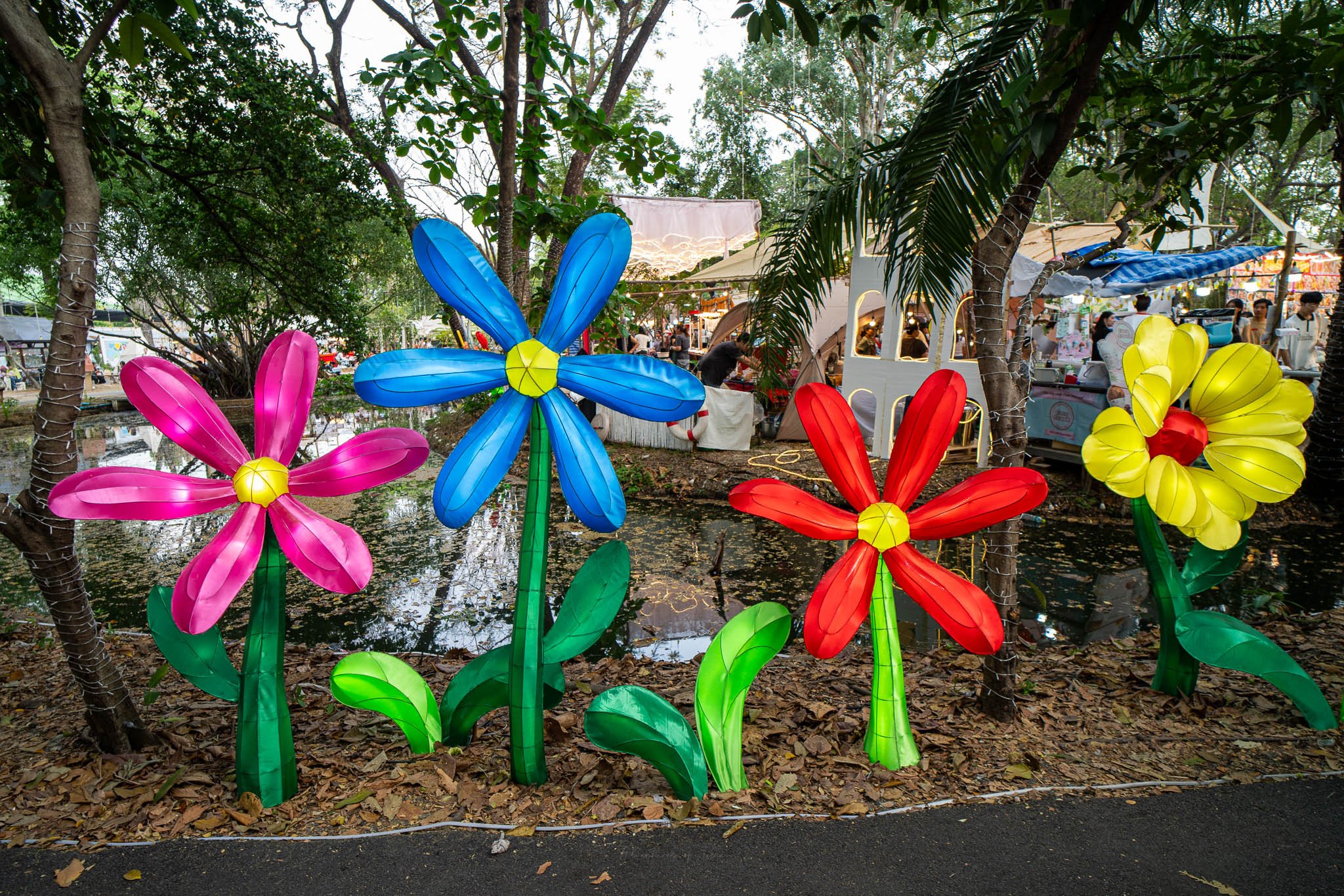 A row of brightly coloured flowers are lit up with lights in a flower bed in the middle of the Kaset Fair in Bangkok.