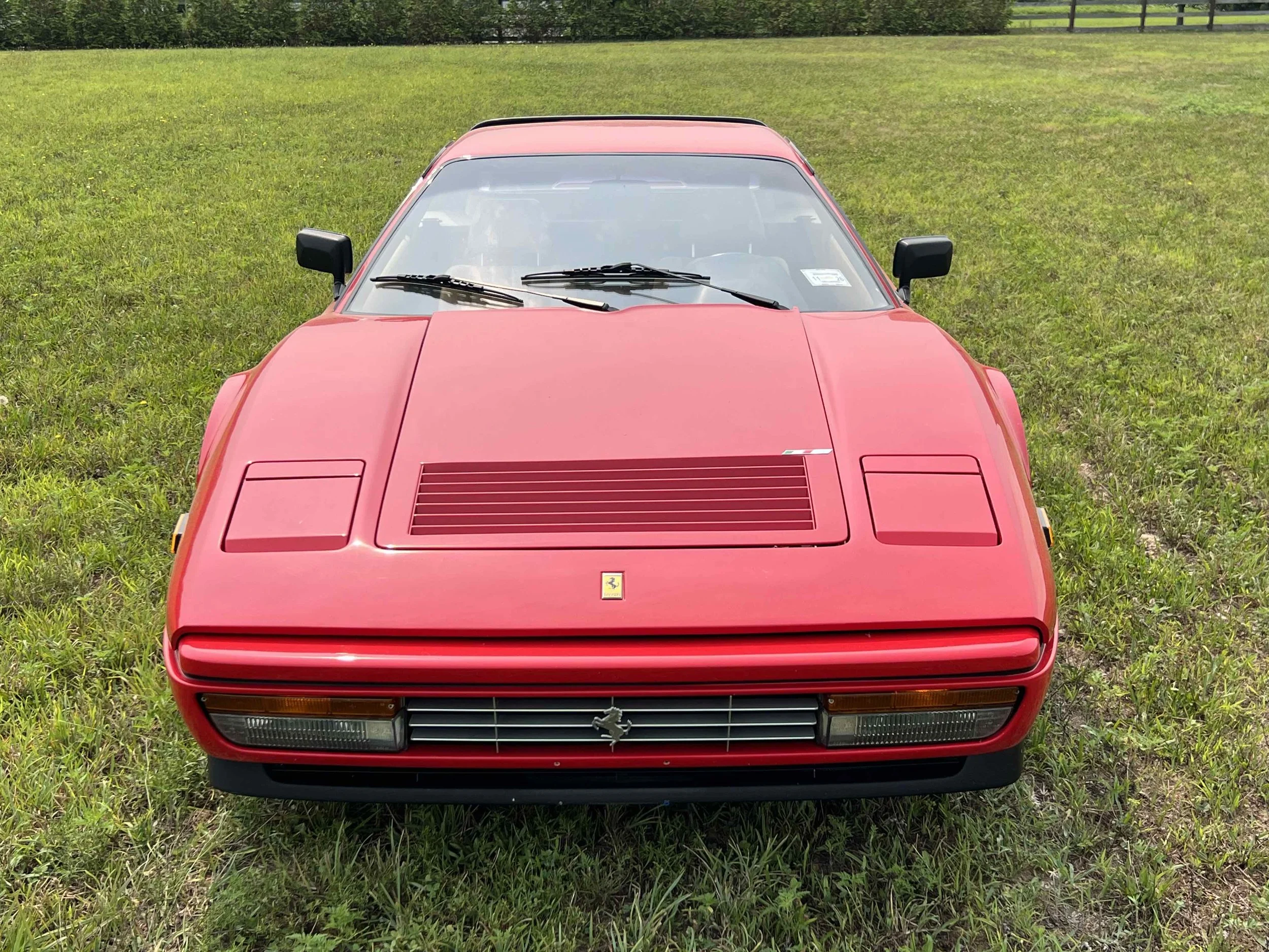 Front view of a red classic Ferrari sports car on a grassy field.