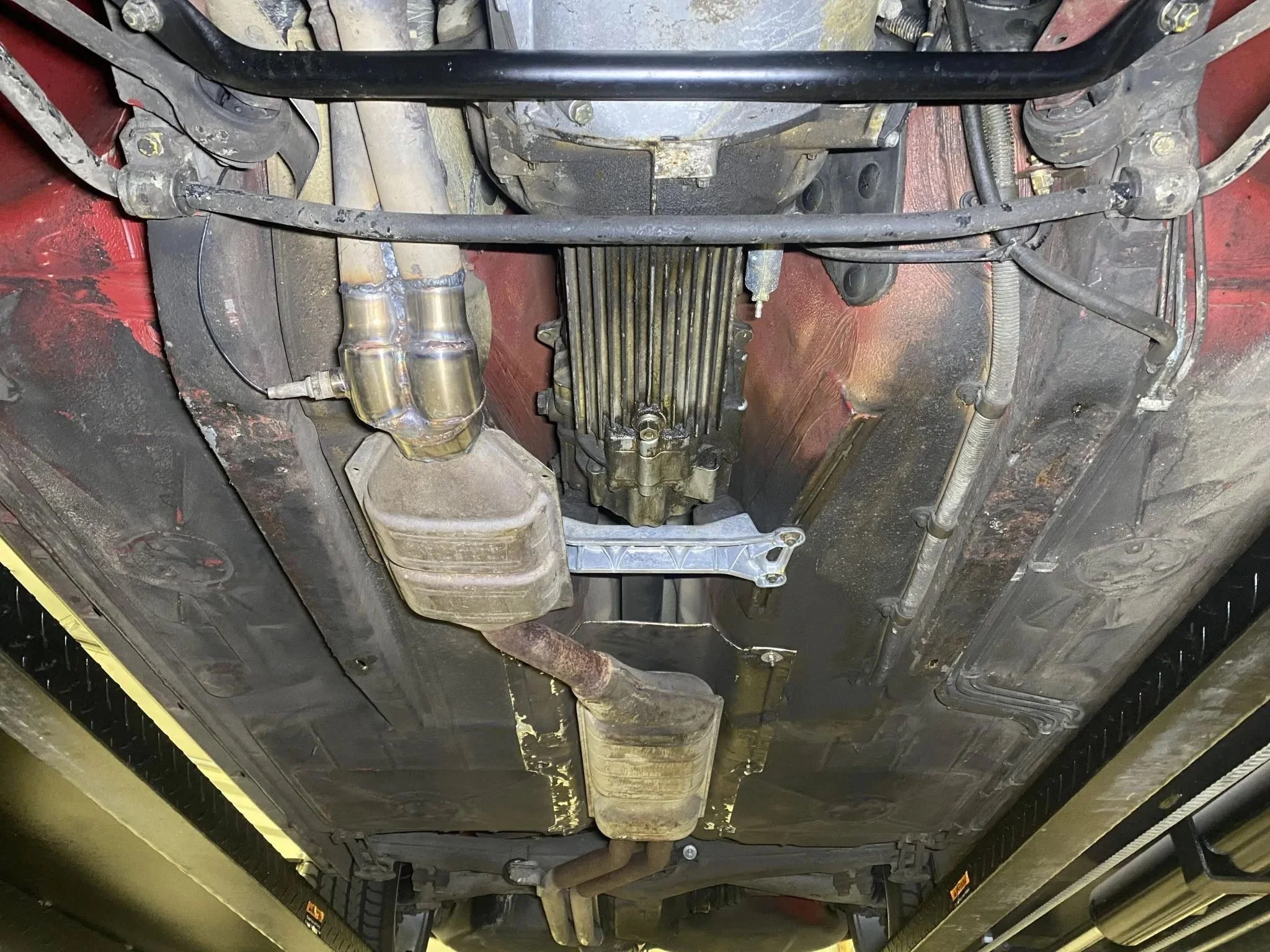 Underneath view of a car showing the exhaust system, transmission, and various pipes and components.
