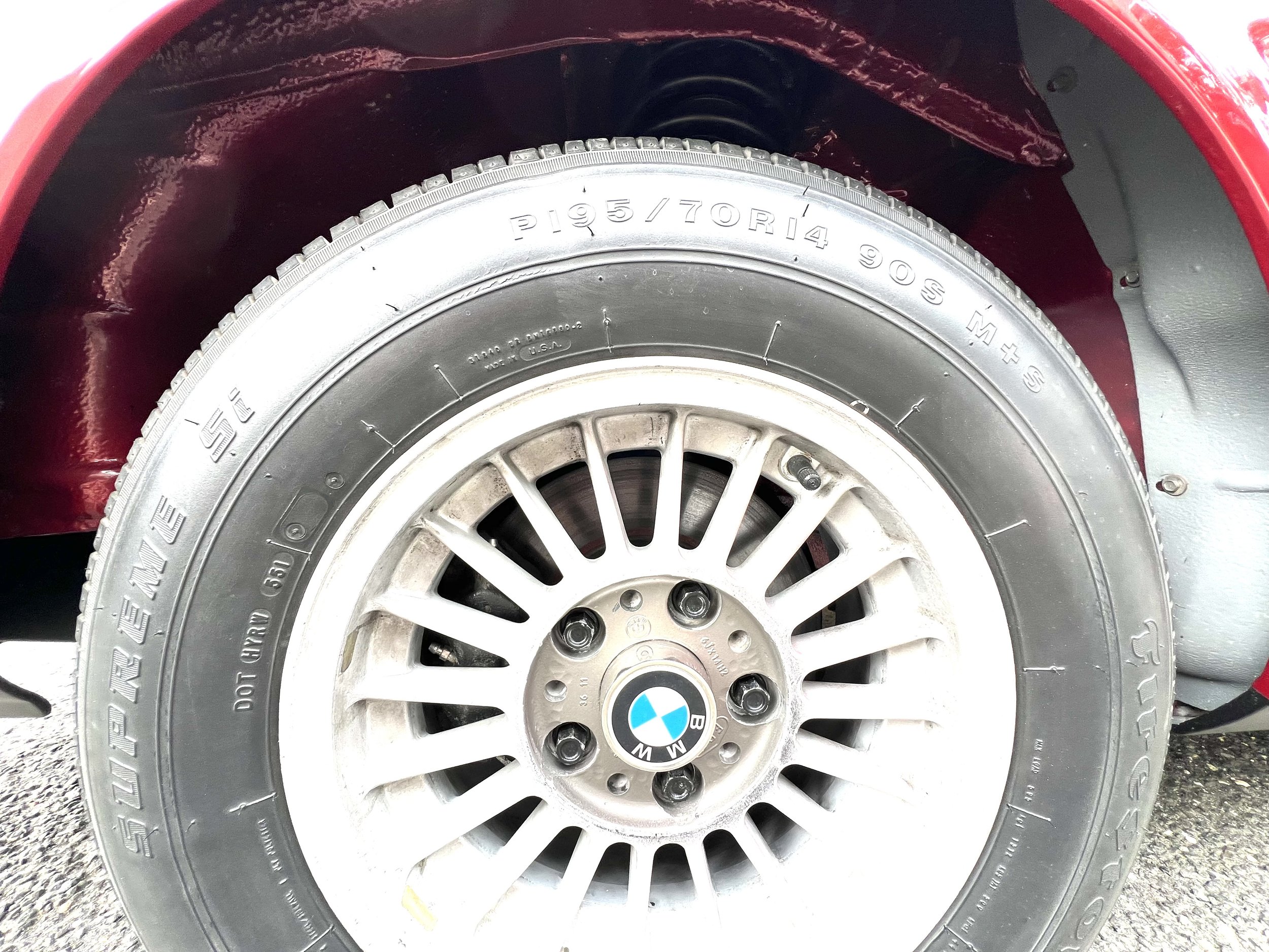 Close-up of a BMW 630 csi car tire and alloy wheel on a red vehicle. The wheel has a BMW logo in the center.