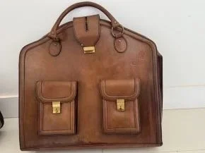 Brown leather Schedoni Ferrari 512 luggage with two front pockets and gold hardware.