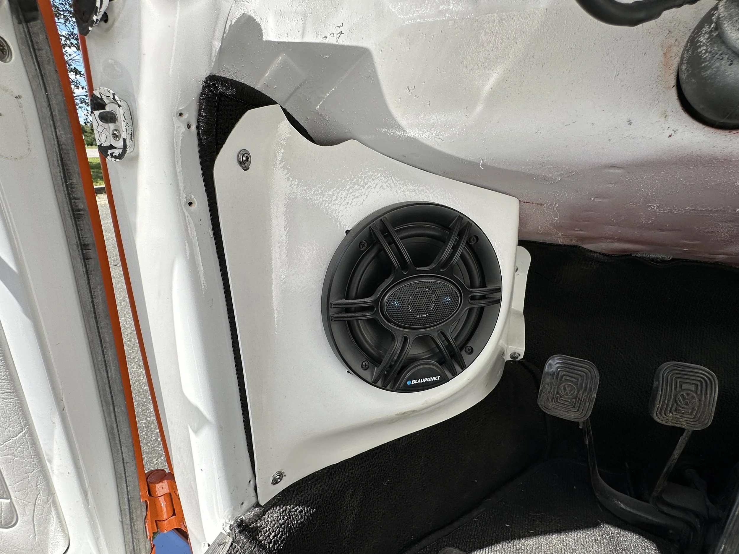 A Blaupunkt speaker installed in a white vehicle interior near the driver's pedals.