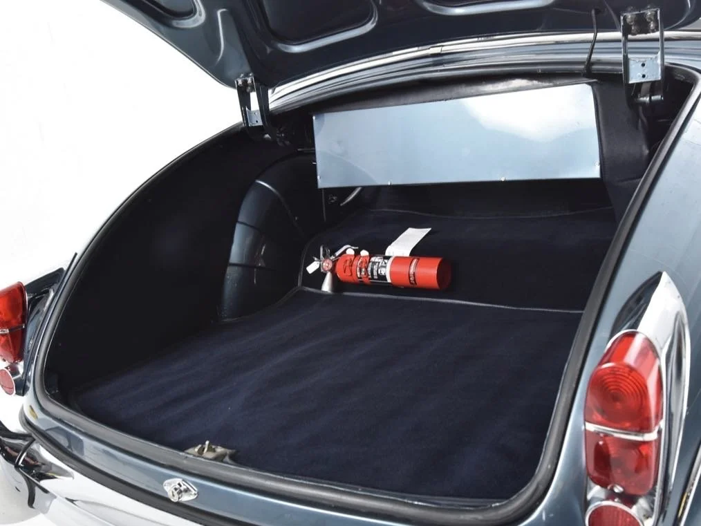 The trunk of a car with a fire extinguisher inside.