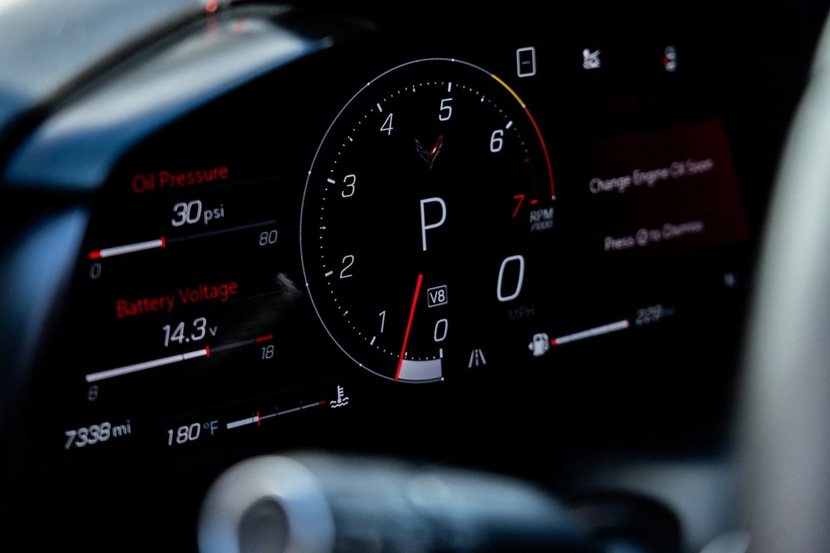 Close-up view of a modern car dashboard displaying the speedometer, tachometer, oil pressure, battery voltage, and other indicators.