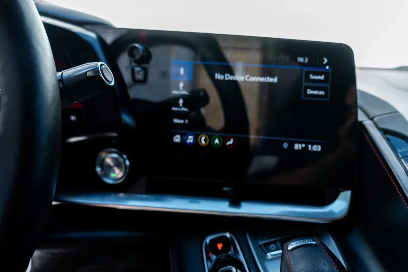 Interior of a modern car dashboard showing a digital display screen, gear shift, and climate control buttons.