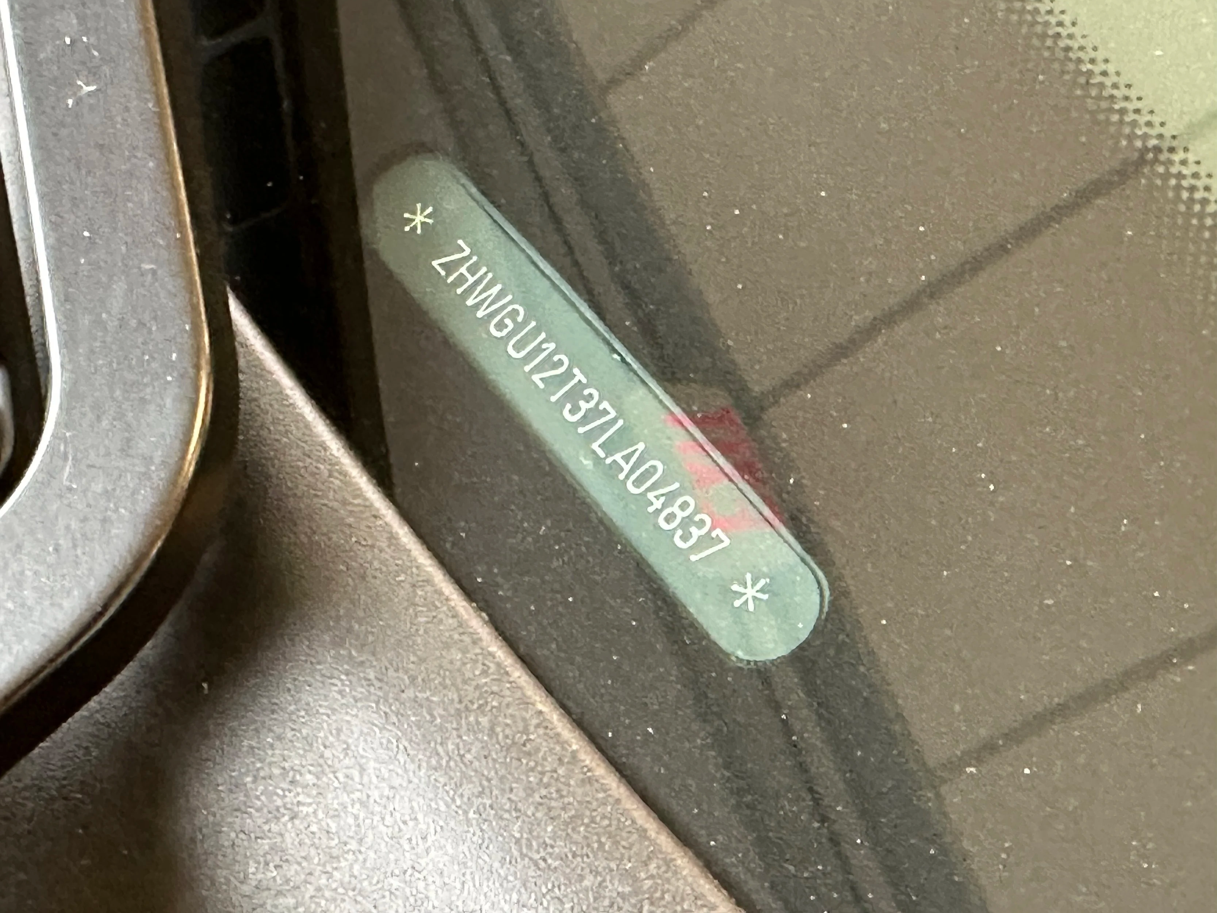A vehicle's dashboard showing a vehicle identification number (VIN) on a sticker under the windshield.