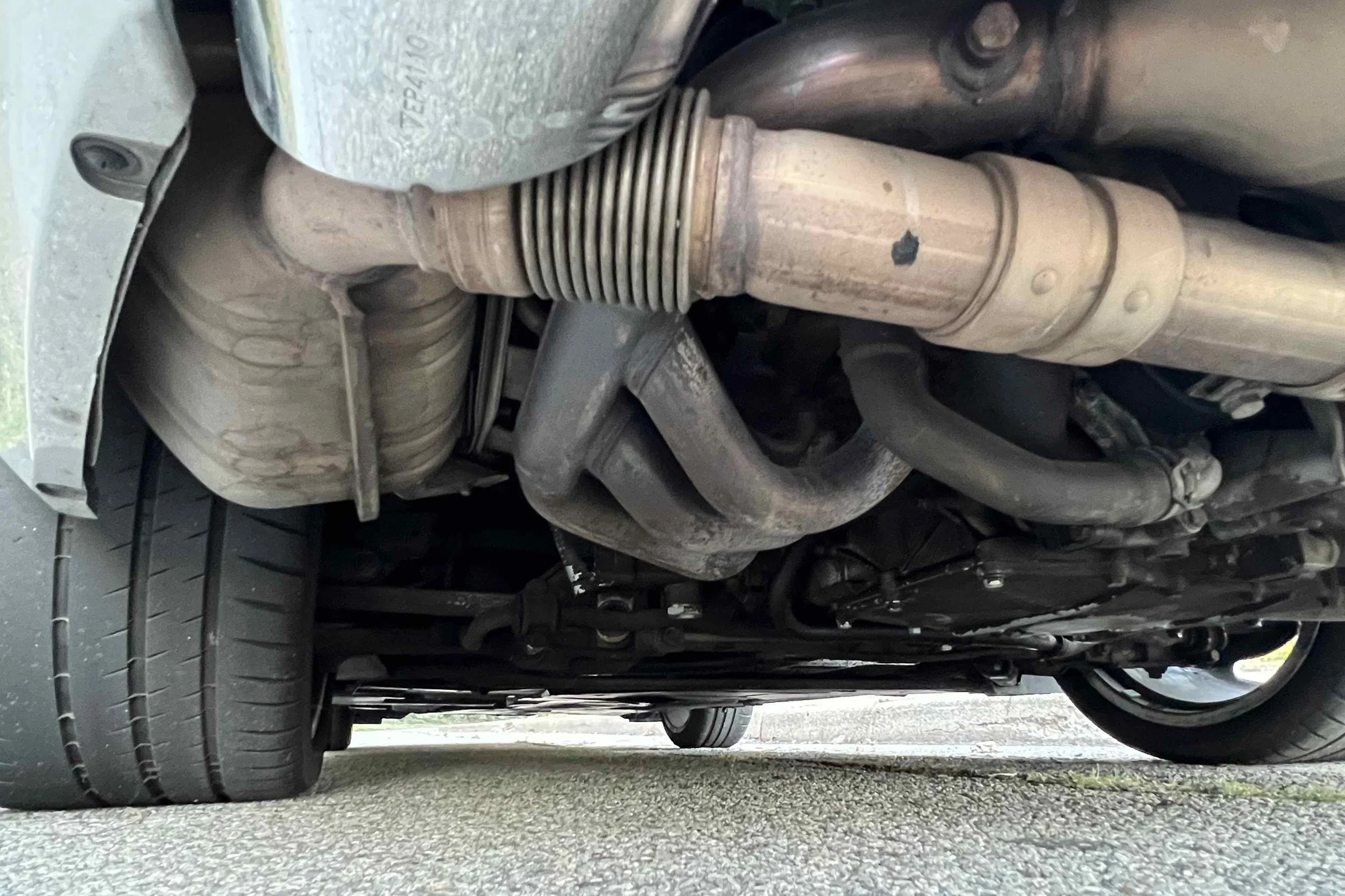 Underneath view of a car showing exhaust system, suspension components, and tires.