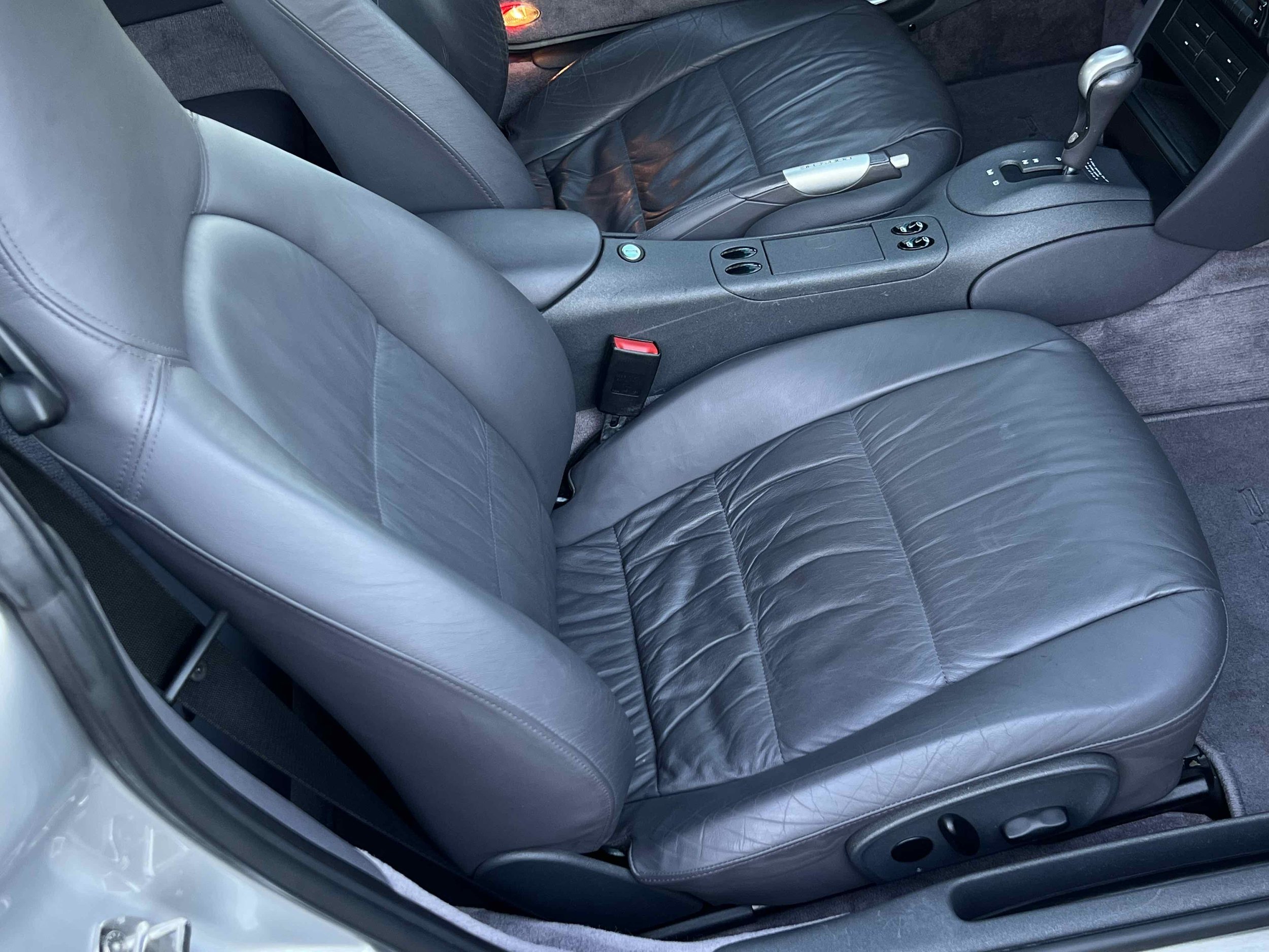 Front passenger seat of a car with gray leather upholstery, with the center console and gear shifter visible.