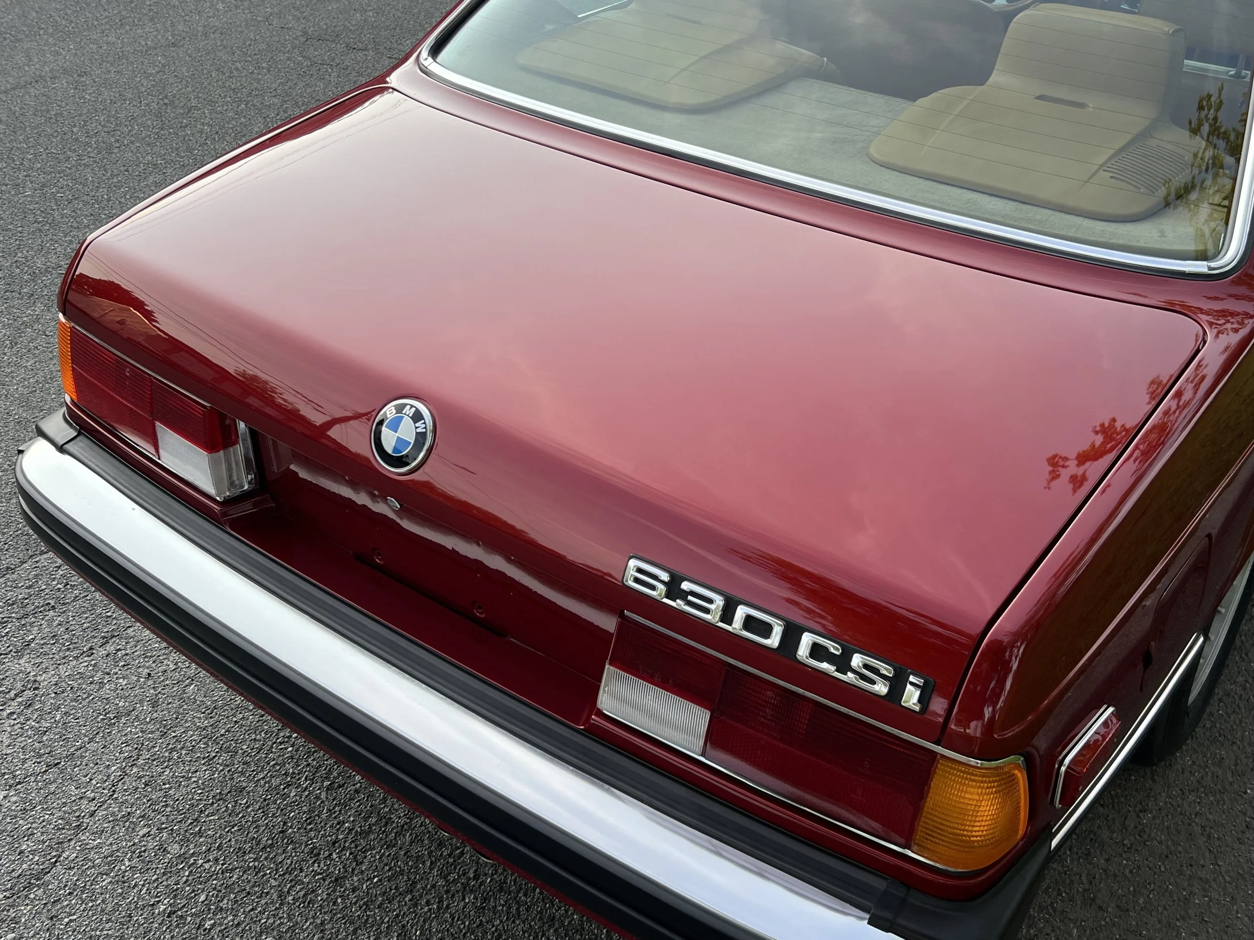 Back of Ruby Red 1977 BMW 630 csi on display in park for sale at FlowHaus
