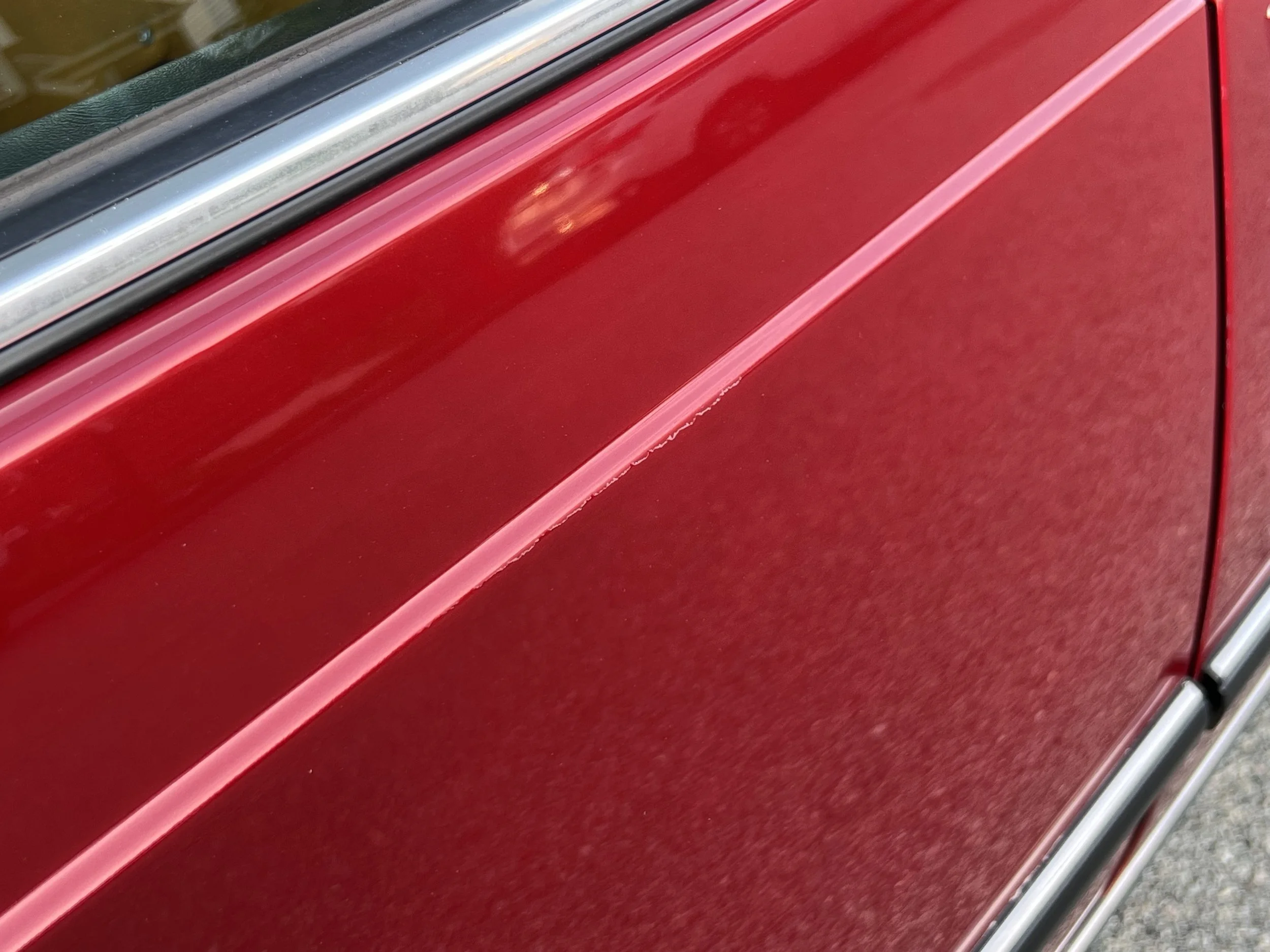 Close-up of a red BMW 630 csi side panel with a visible scratch.