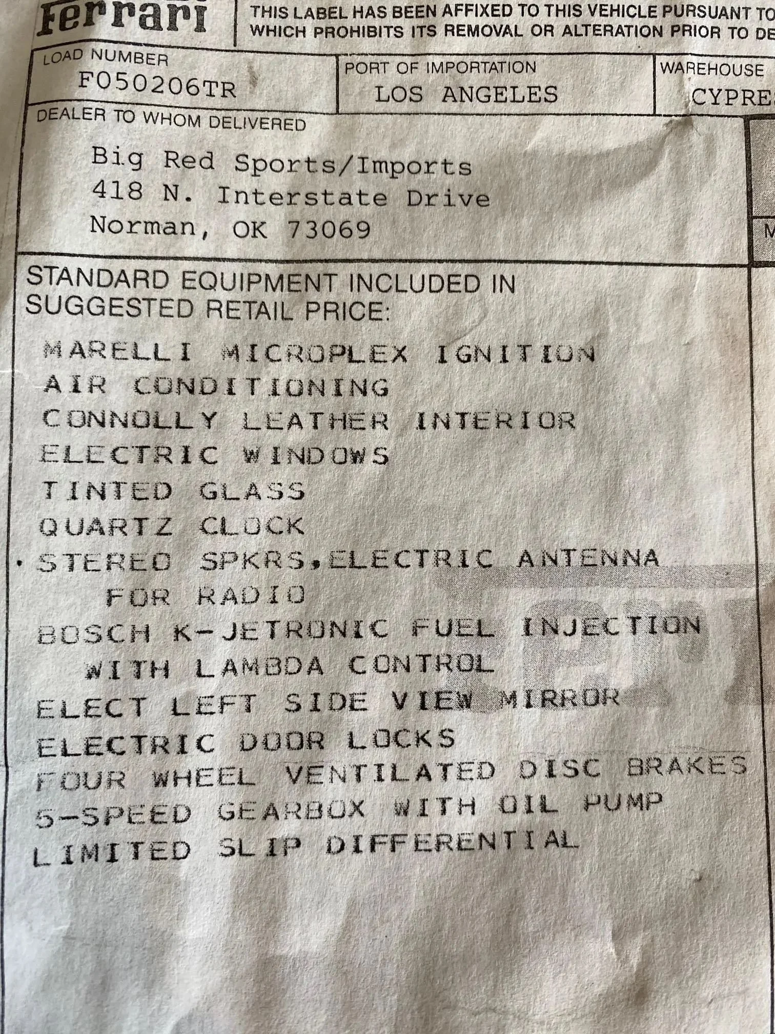 A vehicle shipping label from Ferrari, indicating the load number F050206TR, imported through the Port of Los Angeles, delivered to Big Red Sports/Imports in Norman, Oklahoma. The label lists standard equipment included in the suggested retail price,