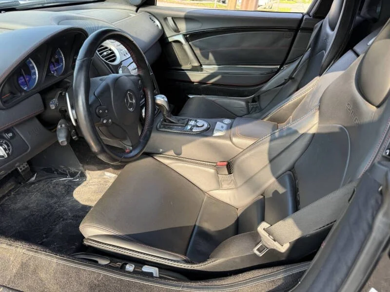 Interior of a black Mercedes-Benz car showing the driver's seat, steering wheel, dashboard, and center console.
