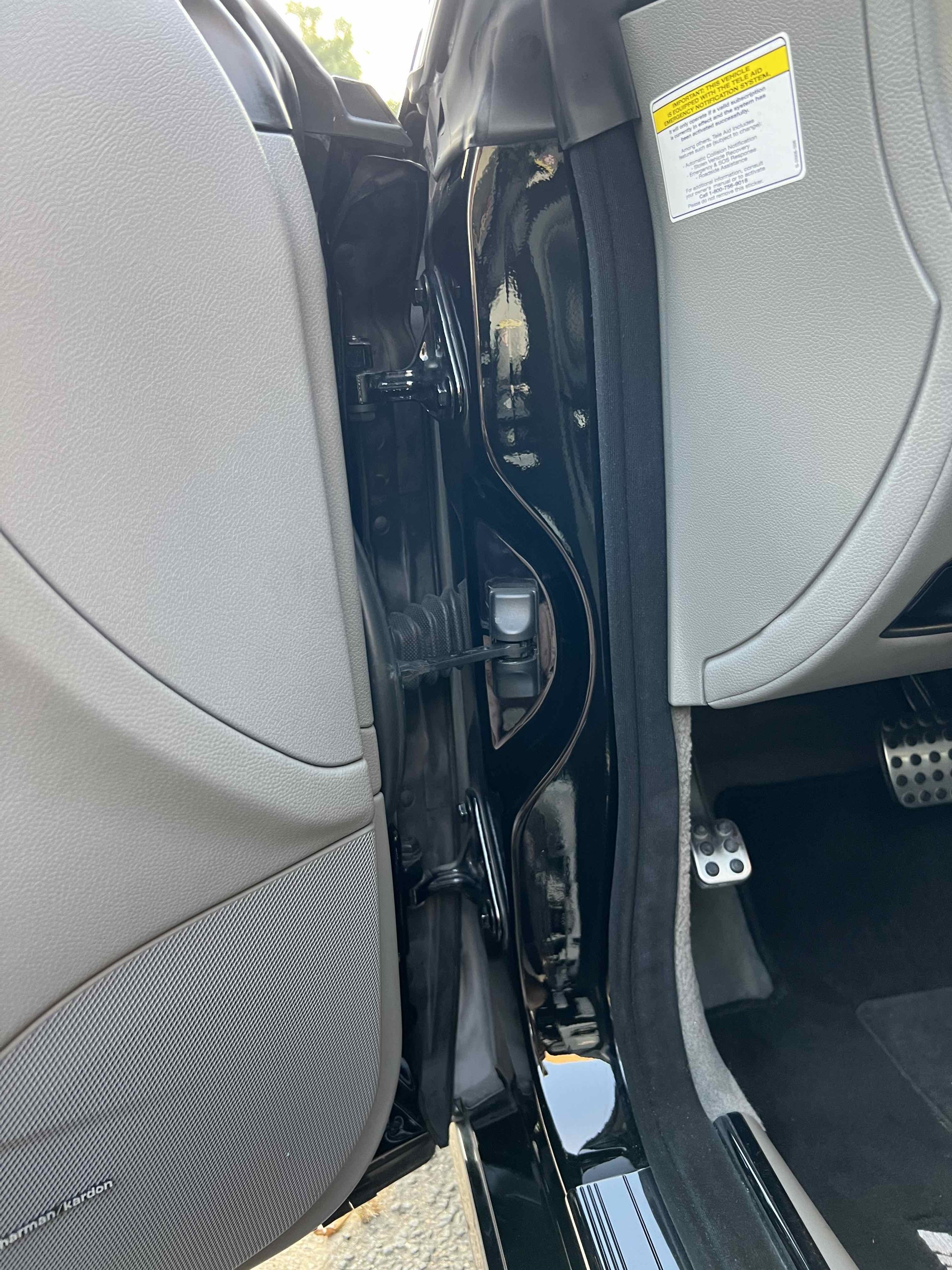 Interior view of a car showing the space between the driver and passenger seats, with visible foot pedals, part of the dashboard, and the side of the car door.