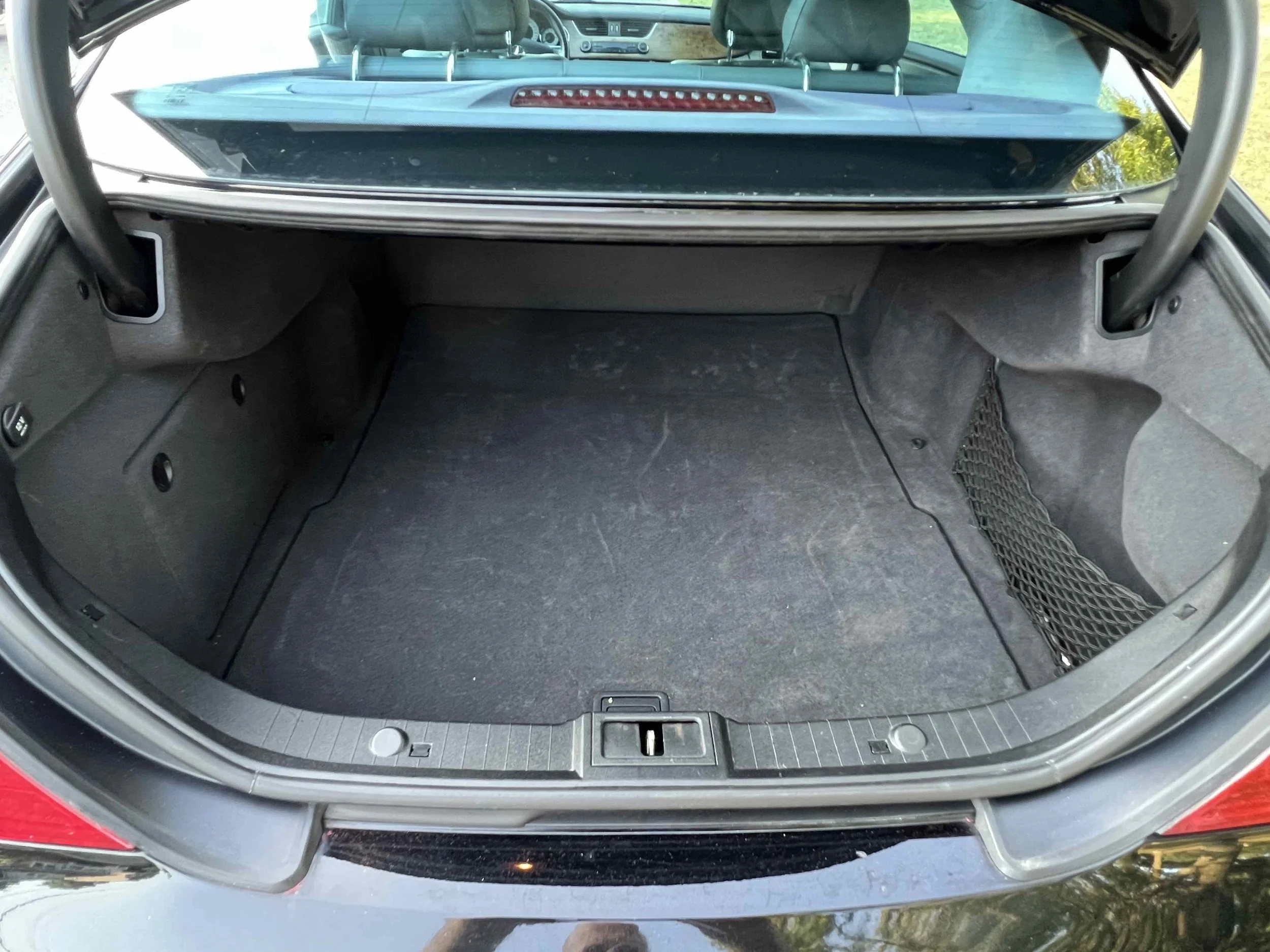 Open car trunk with empty interior and a small mesh storage pocket on the right side.