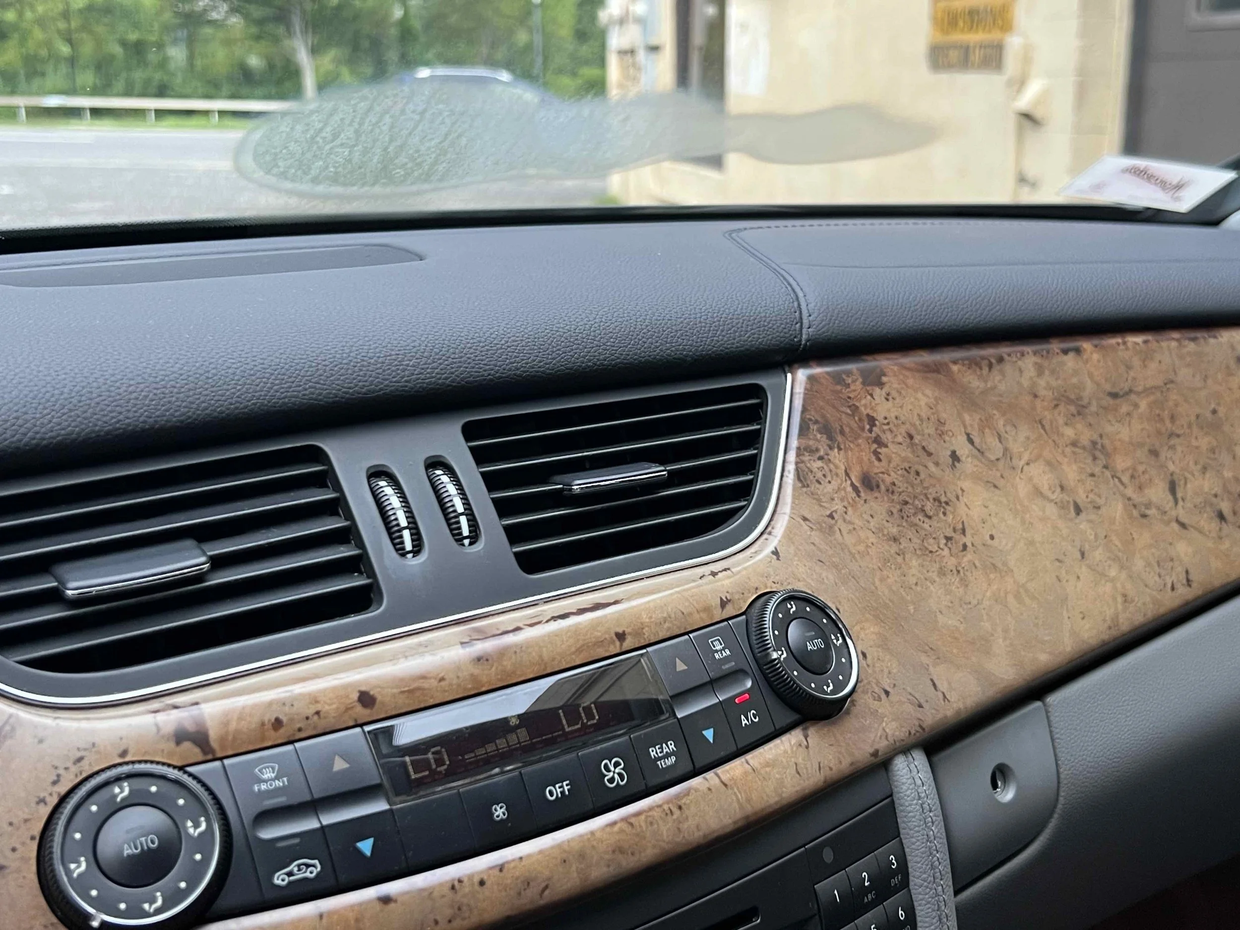 Interior of a car showing the dashboard with wood grain panel, air vents, and climate control system.