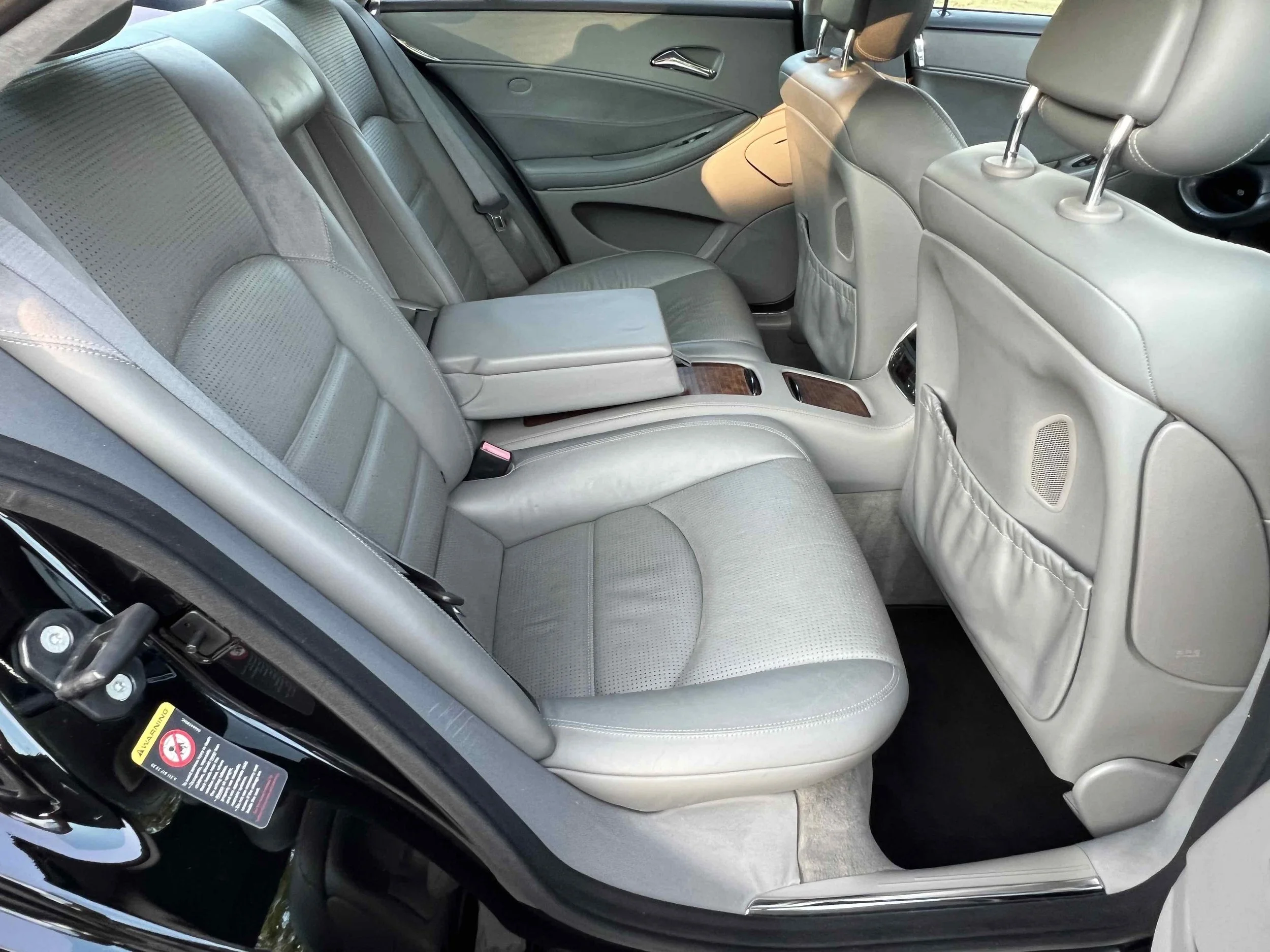 Interior view of a car's backseat area with light gray leather seats, headrests, and storage pockets on the back of the front seats.