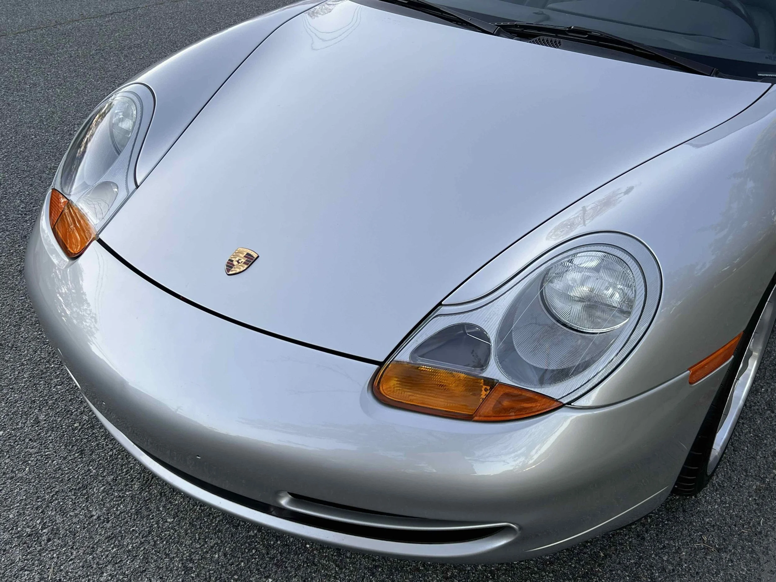 Front view of a silver Porsche sports car showing the hood, headlights, and part of the front bumper.