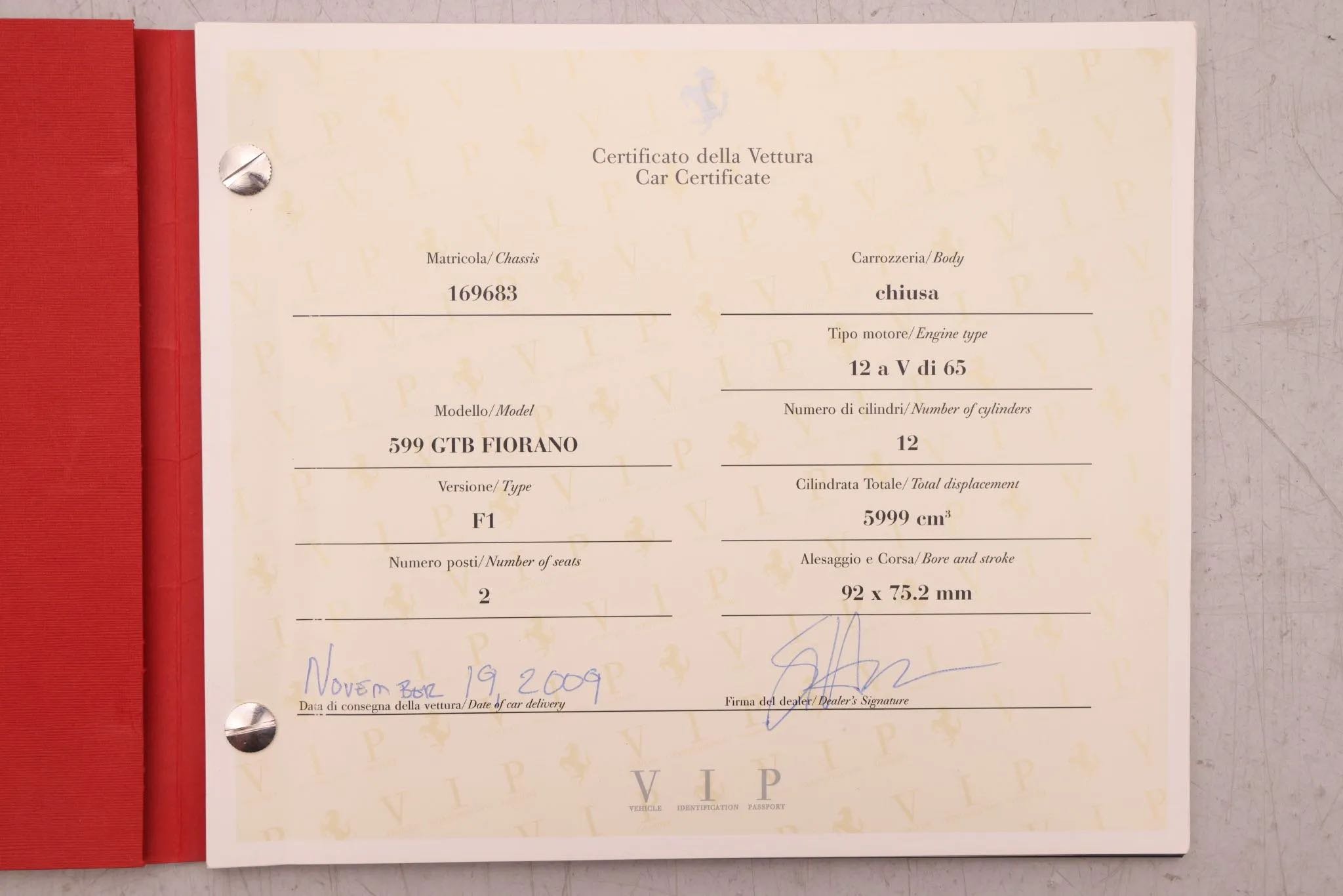 Car certificate showing model 599 GTB Fiorano, engine 12 V di 65, year 2009, 2 seats, 5999 cc, signed by dealer, with a red cover on the left side.