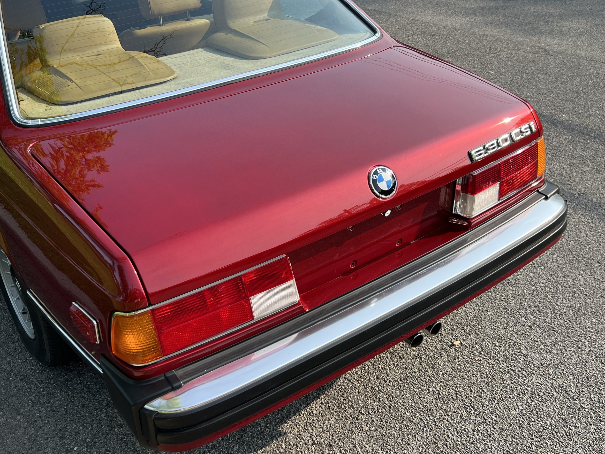 Back of Ruby Red 1977 BMW 630 csi on display in park for sale at FlowHaus