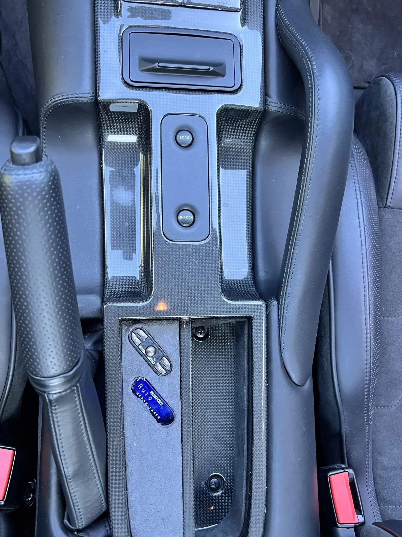 Car center console with lock and unlock buttons, a small storage compartment, and an interior woodgrain trim.