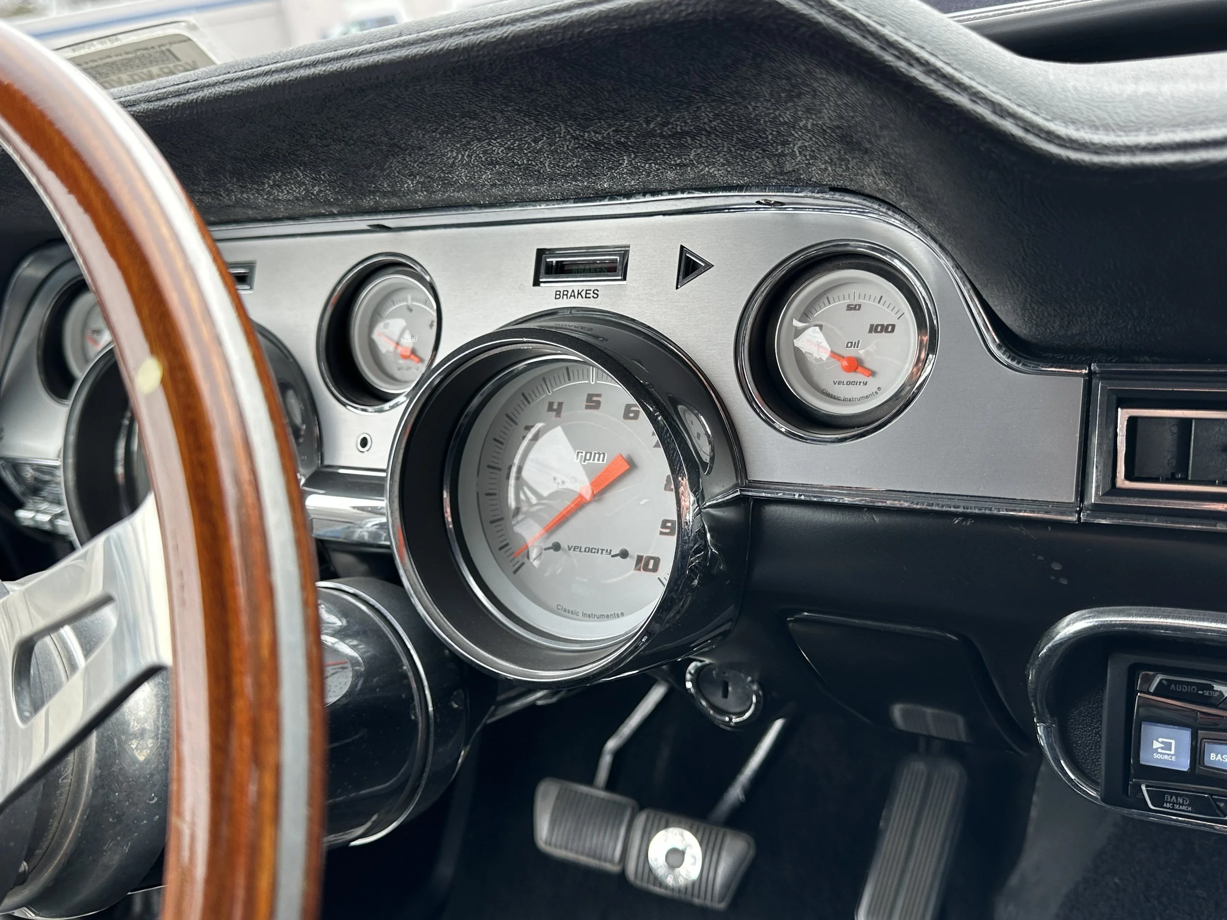 Close-up of vintage car dashboard with gauges including RPM, speed, oil pressure, and brake indicator.