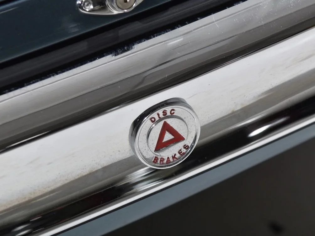 Close-up of a circular emblem labeled 'Disc Brakes' with a red triangle in the center, attached to a metallic vehicle part.