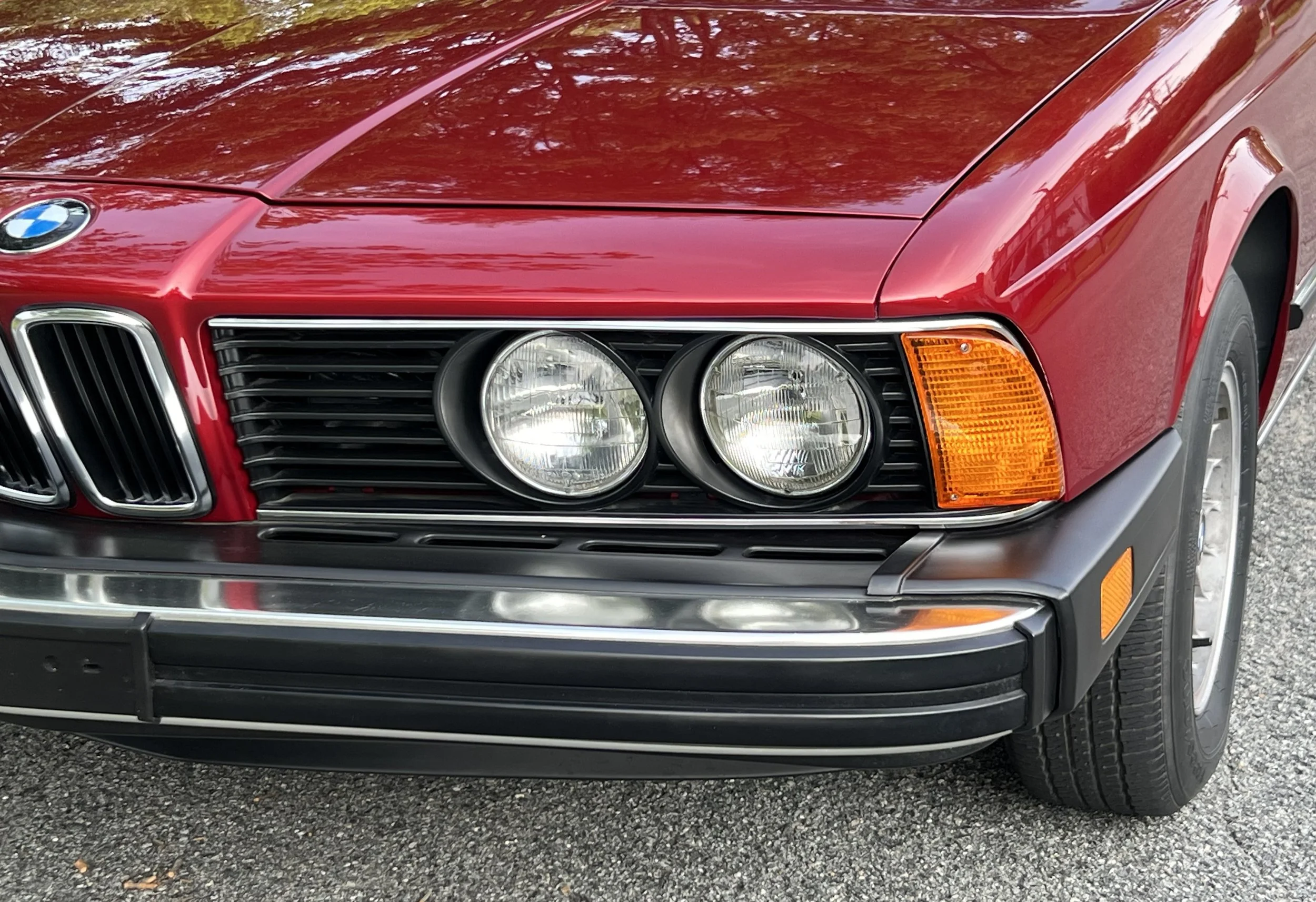 Front of Ruby Red 1977 BMW 630 csi on display in park for sale at FlowHaus