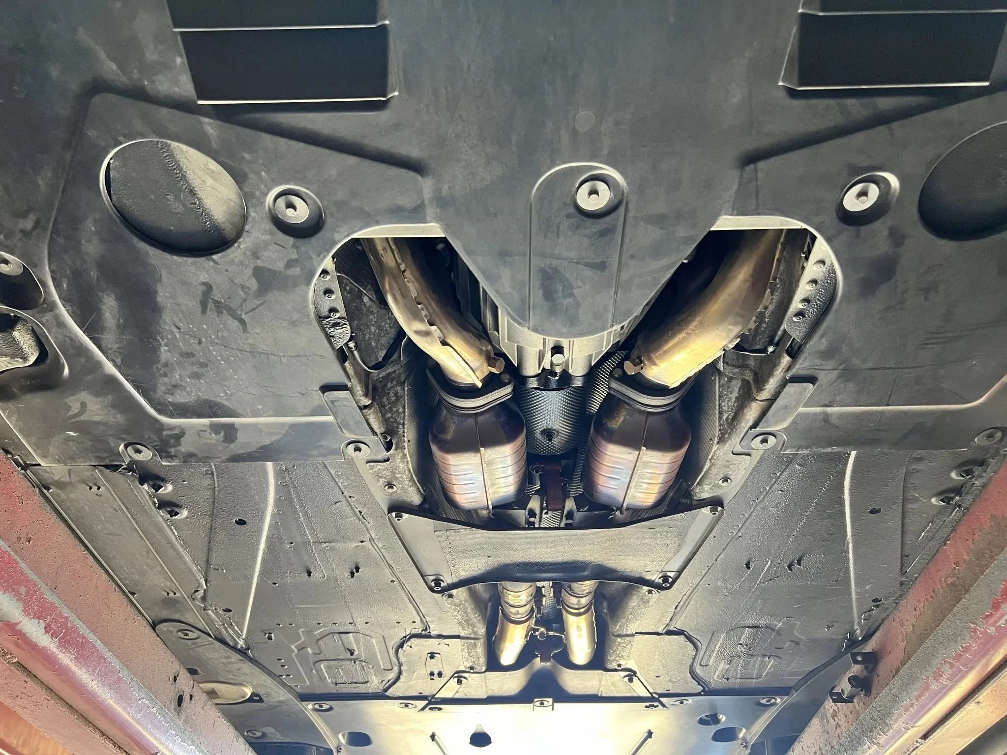 Underbelly of a car showing exhaust system and undercarriage.