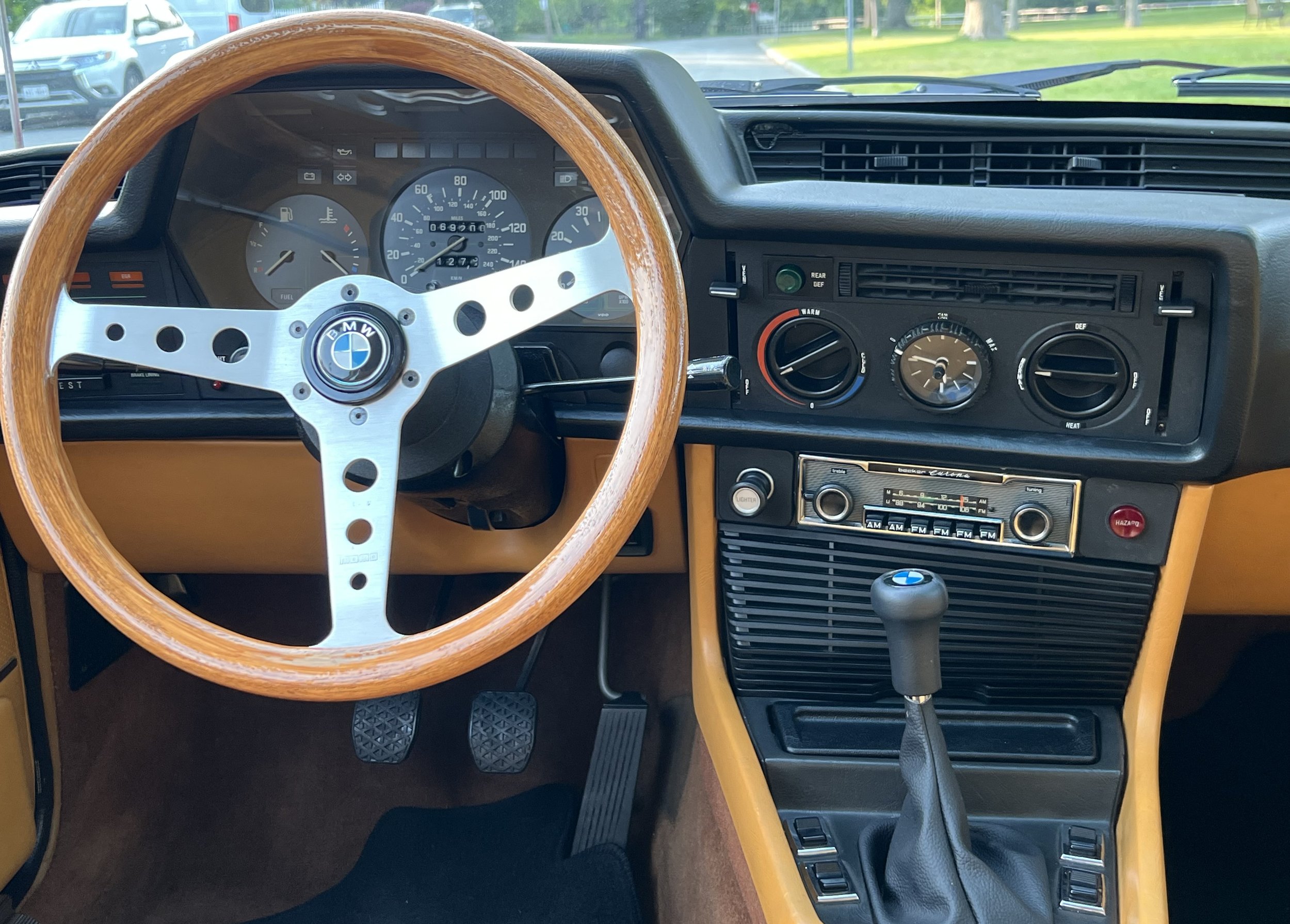 The interior dashboard of a vintage BMW BMW 630 csi car with a wooden steering wheel, analog gauges, and classic controls.
