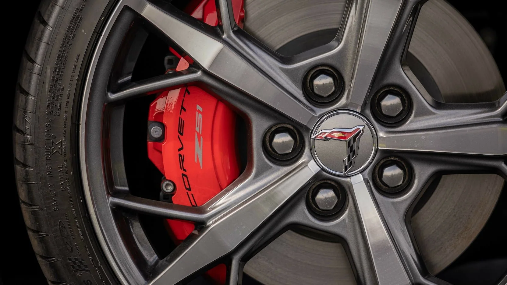 Close-up of a Chevrolet Corvette Z51 brake caliper behind a silver alloy wheel with a Chevrolet logo at the center.