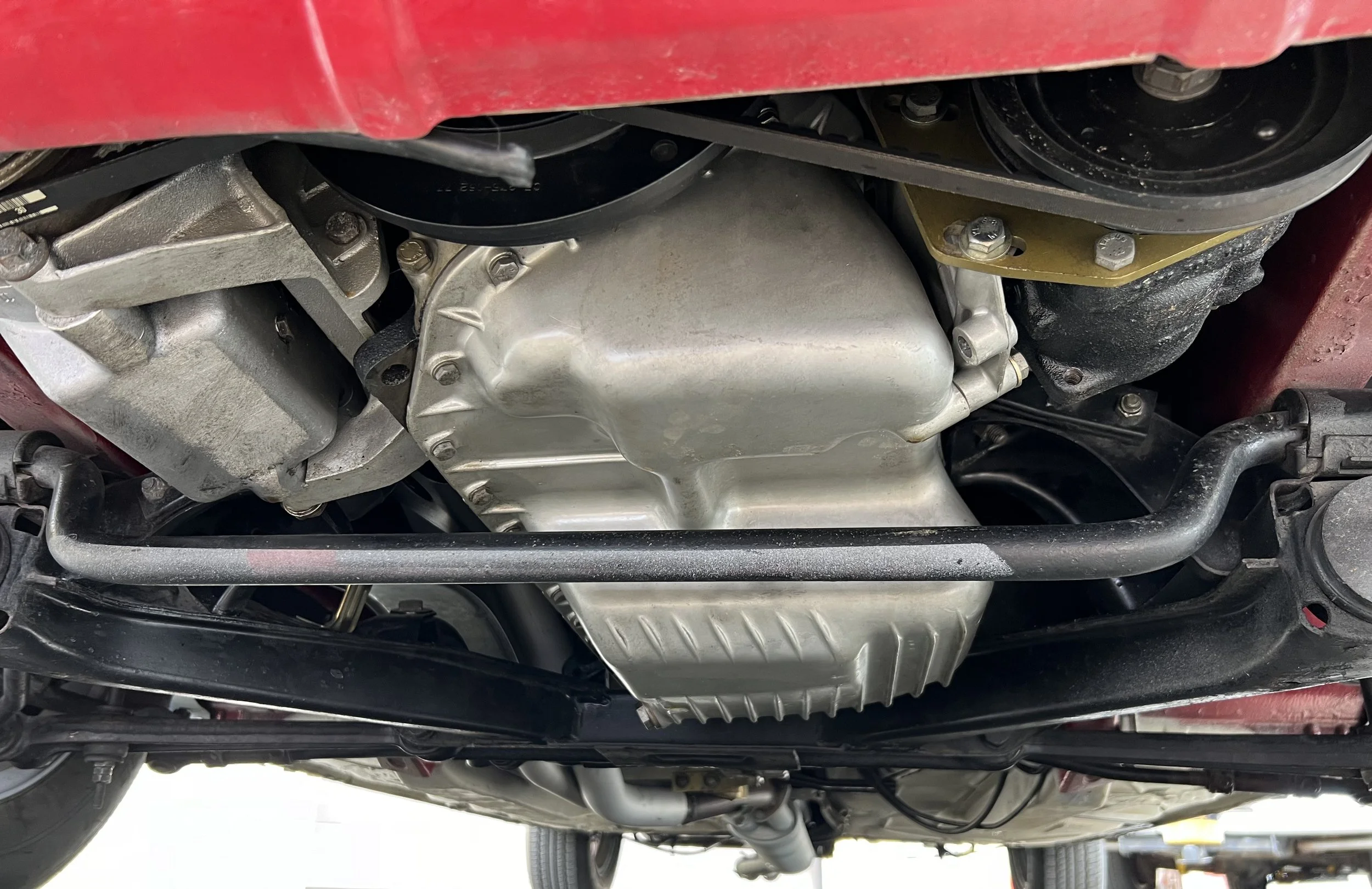 Underneath view of a 1977 BMW 630 csi showing the oil pan, transmission, and suspension components.