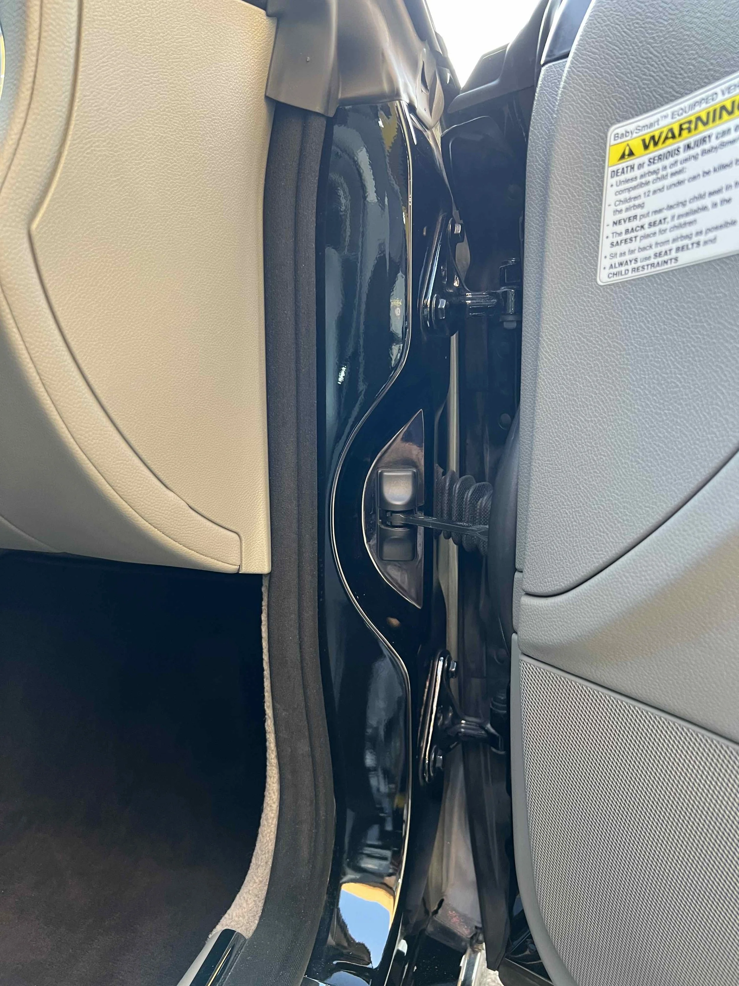 Close-up of a black door frame with safety stickers and a door latch.