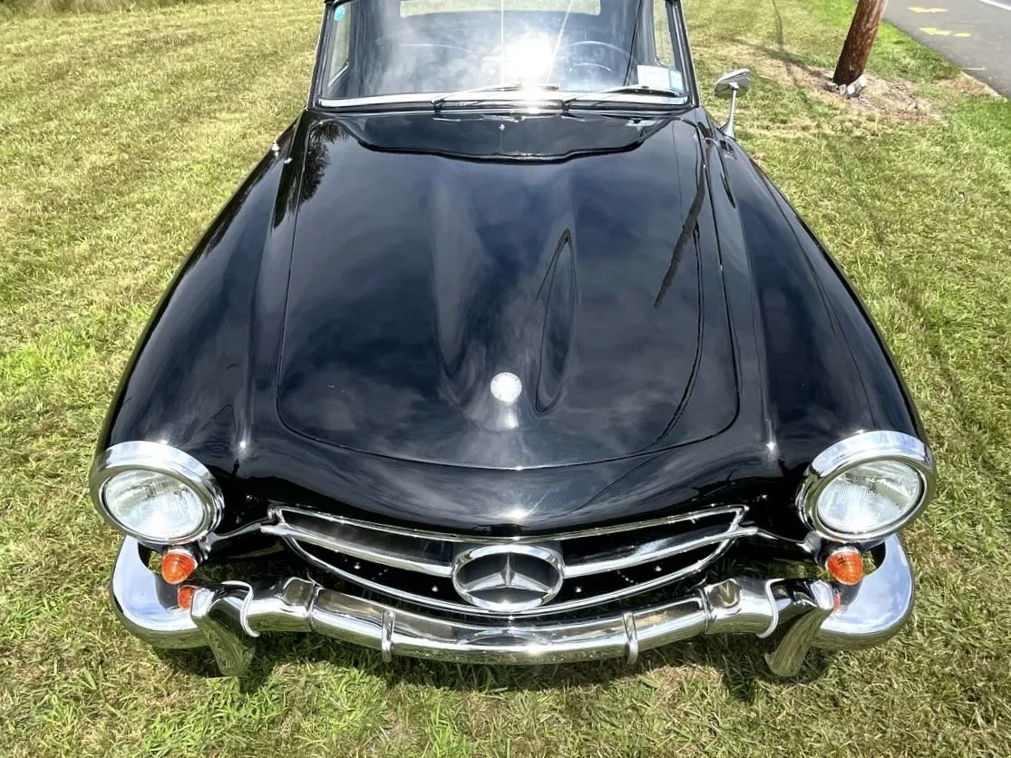 Front view of a vintage black Mercedes-Benz car parked on grass.