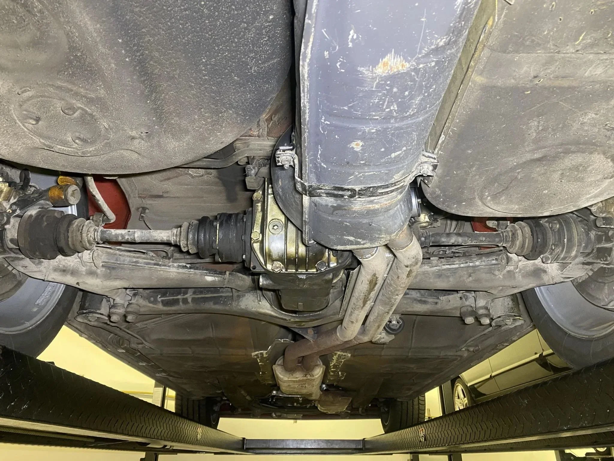 Underneath view of a car showing the drivetrain, axles, and exhaust system.