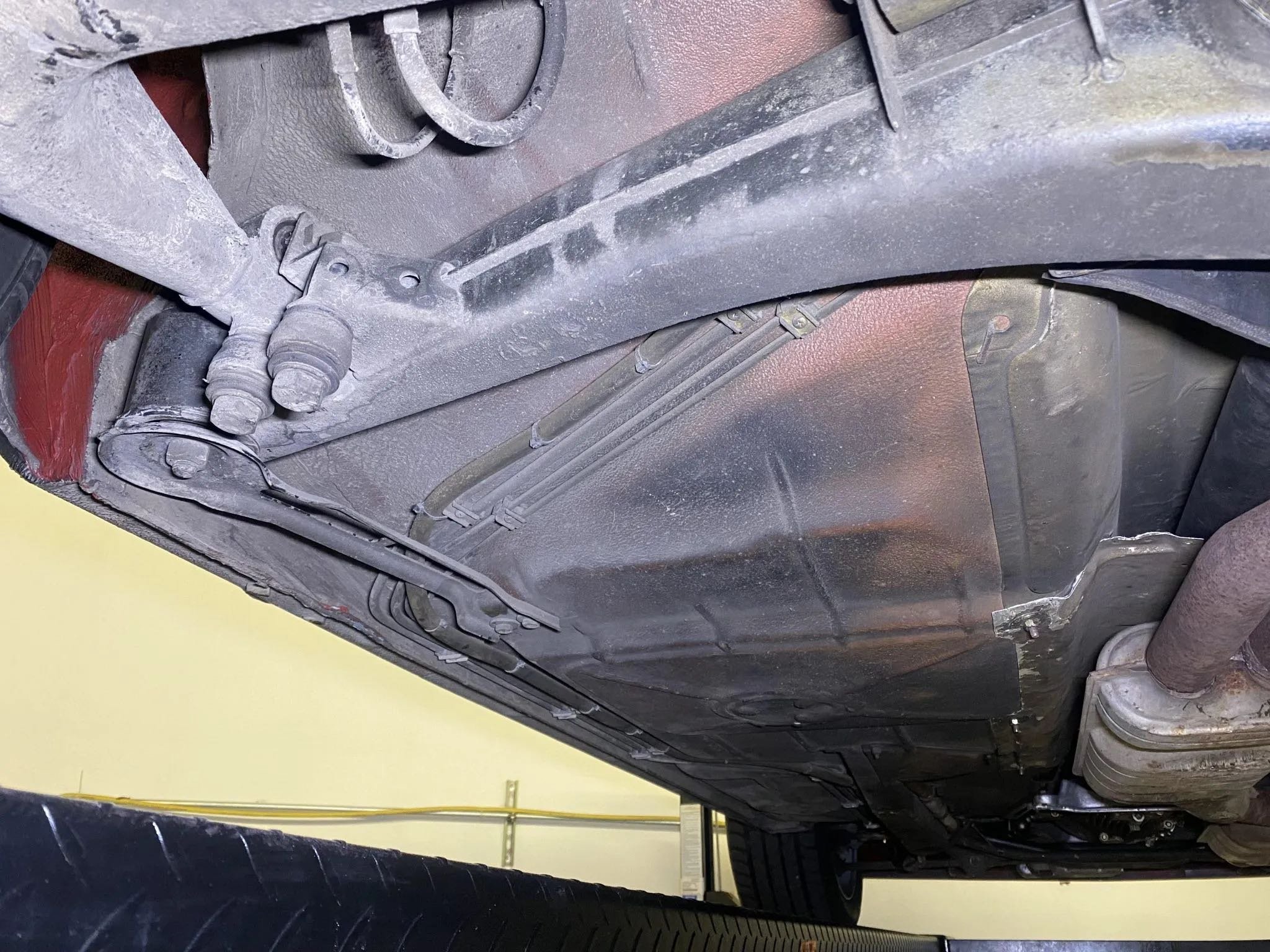 View of the underside of a vehicle showing the oil pan, exhaust pipe, and suspension components.