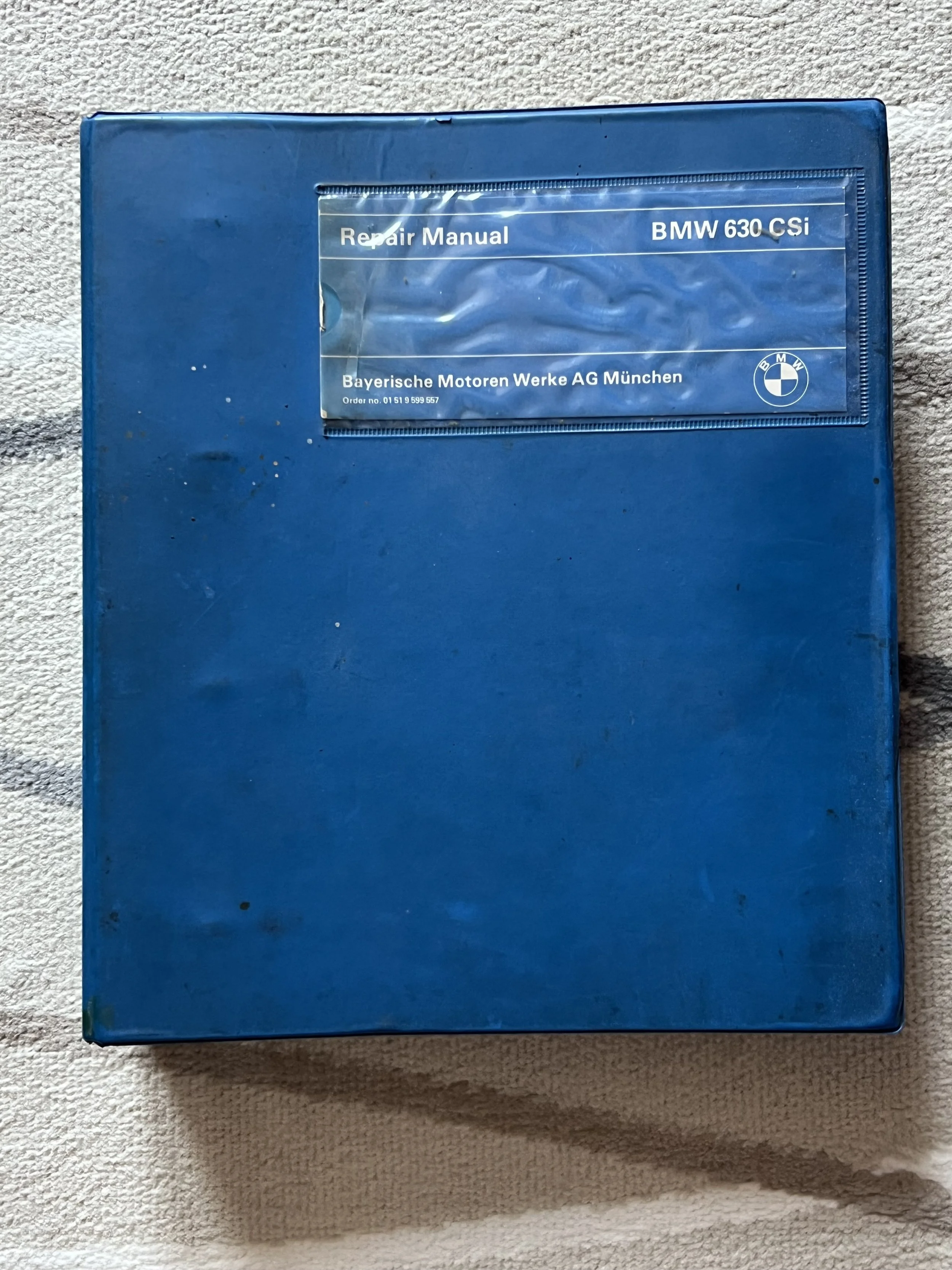 Blue repair manual for a BMW 630 CSI on a textured surface
