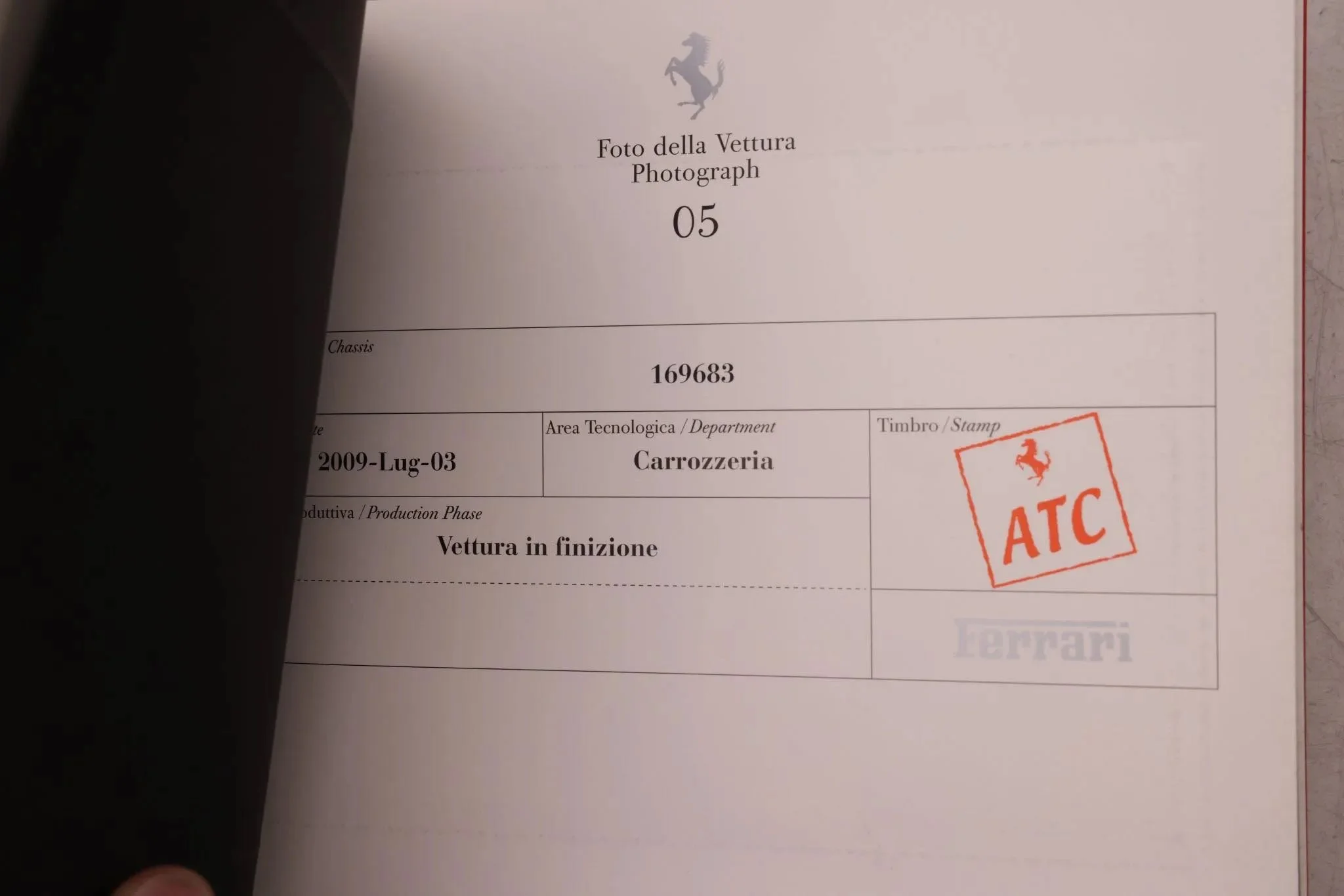 Page from a car document showing a Ferrari logo, the number 169683, and the text 'Vettura in finzione' with a red stamp labeled 'ATC' and a faint Ferrari logo.
