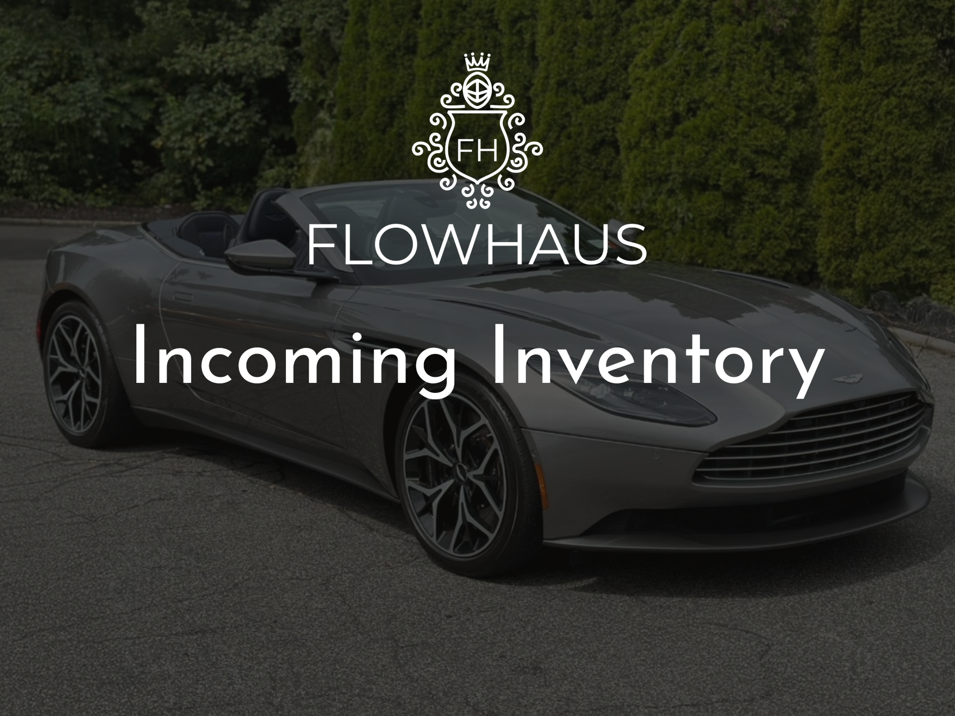 Gray convertible sports car parked on the side of a road with green bushes in the background, overlayed with 'Flowhaus Incoming Inventory' text.