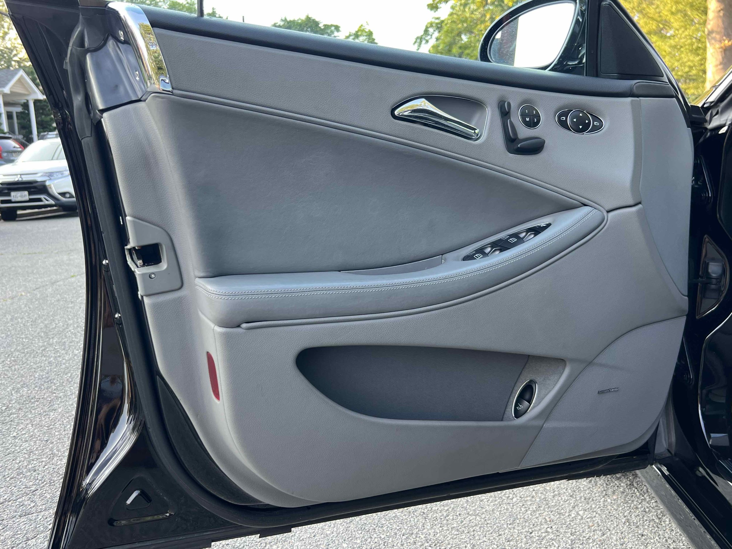 Close-up of a car door interior with gray panel, window controls, door handle, and side mirror visible.