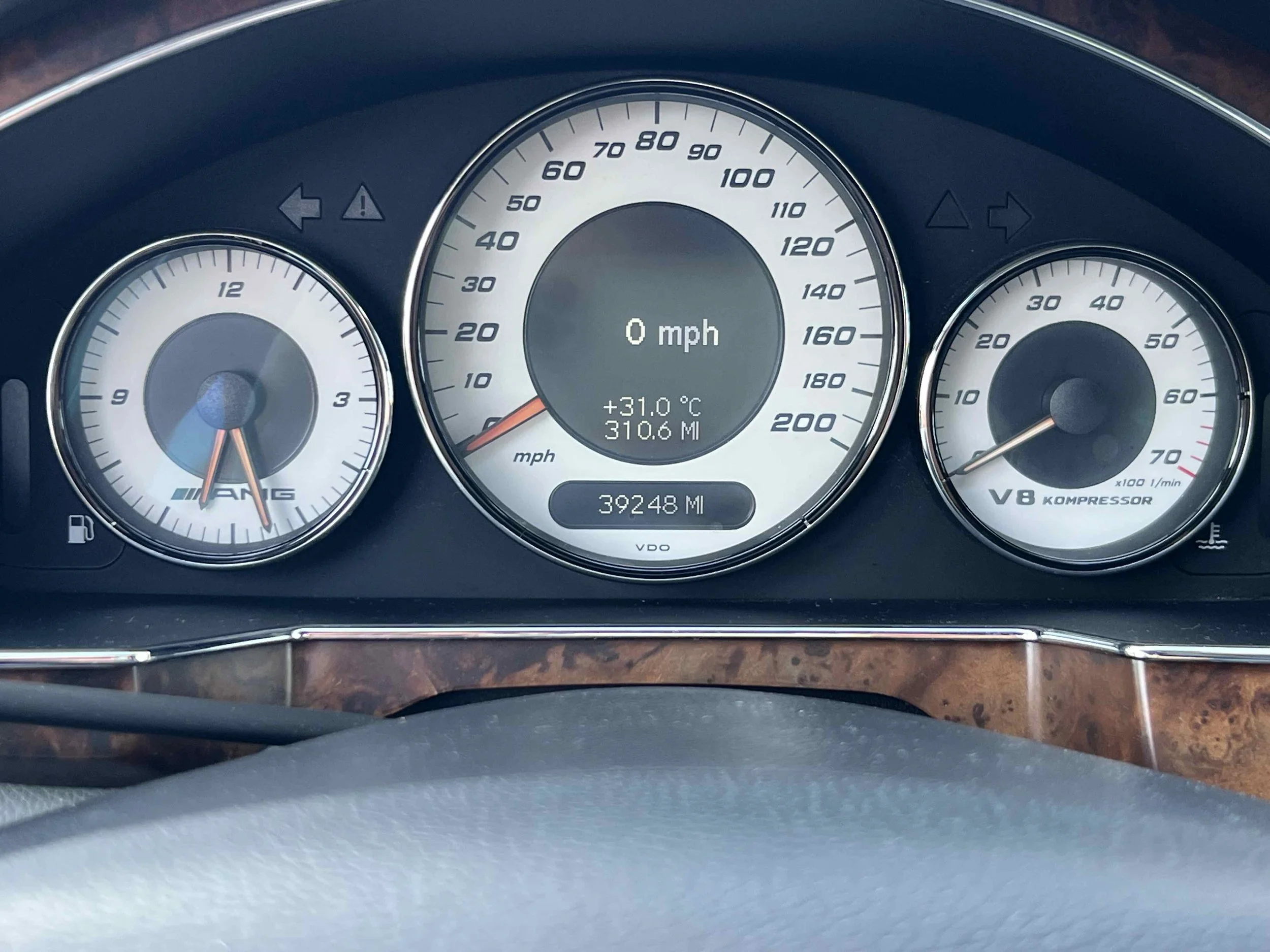 Car dashboard showing speed of 0 mph, odometer reading 39,248 miles, outside temperature 31.0°C, and a fuel gauge with a low fuel warning