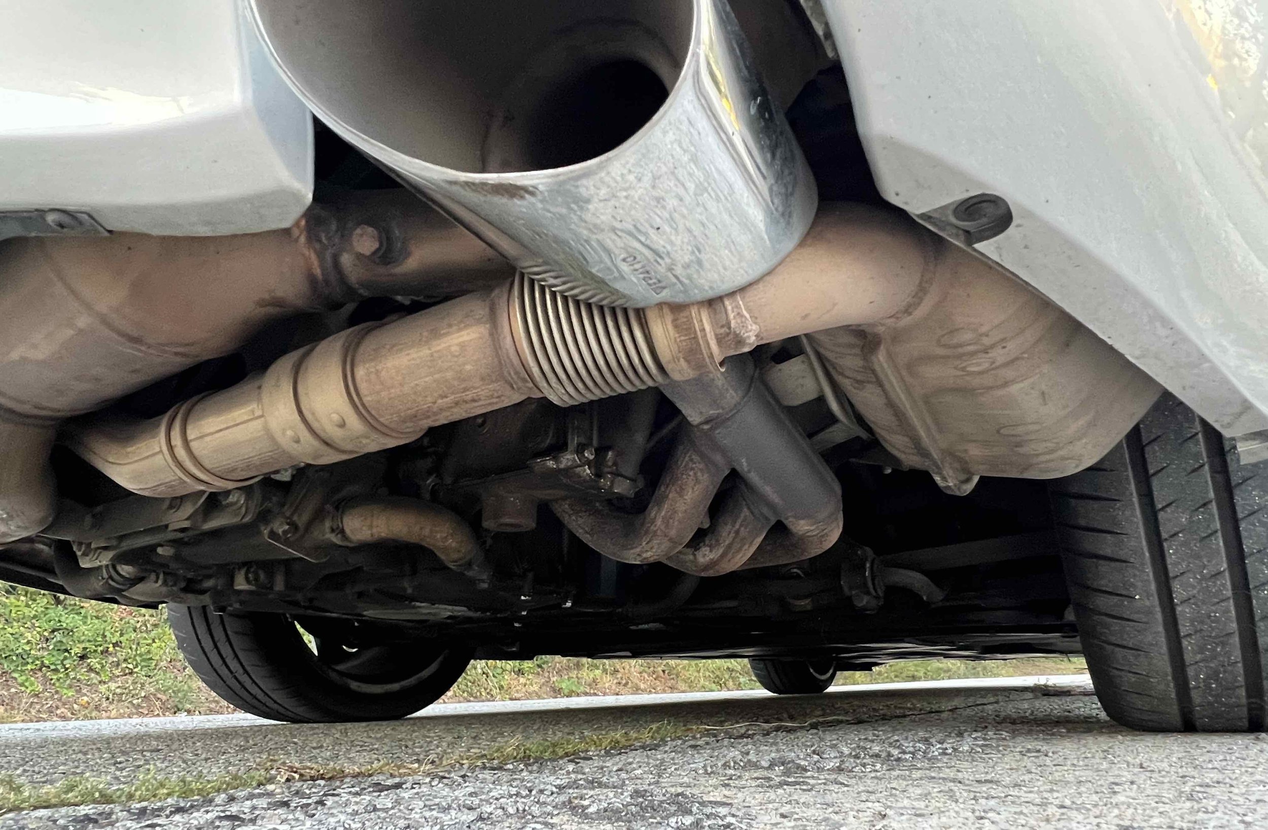 Underneath a car showing parts of the exhaust system and the underside of the vehicle, including the exhaust pipe and muffler.